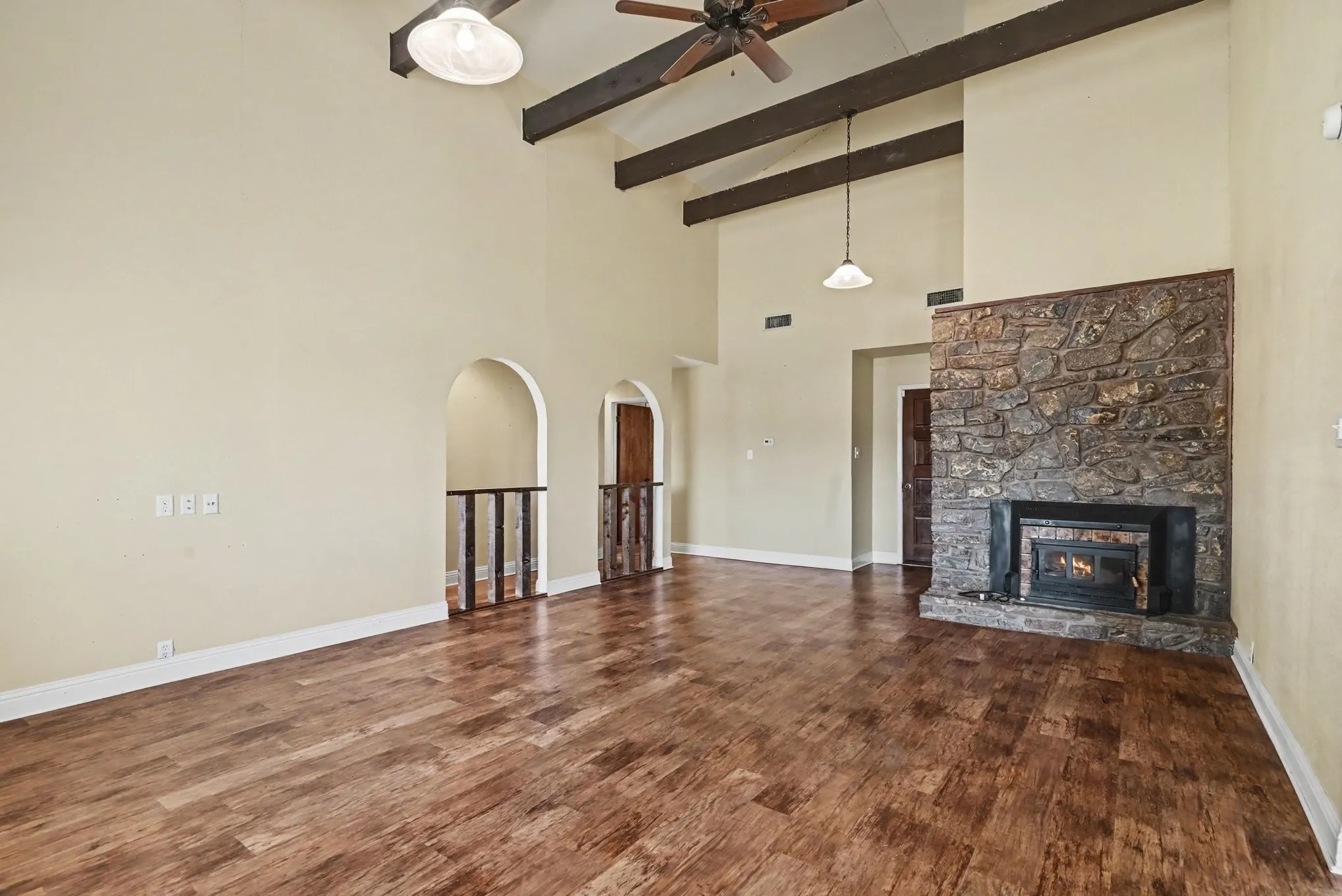 Wood-finish flooring with recessed lighting, an arched doorway, and a ceiling fan