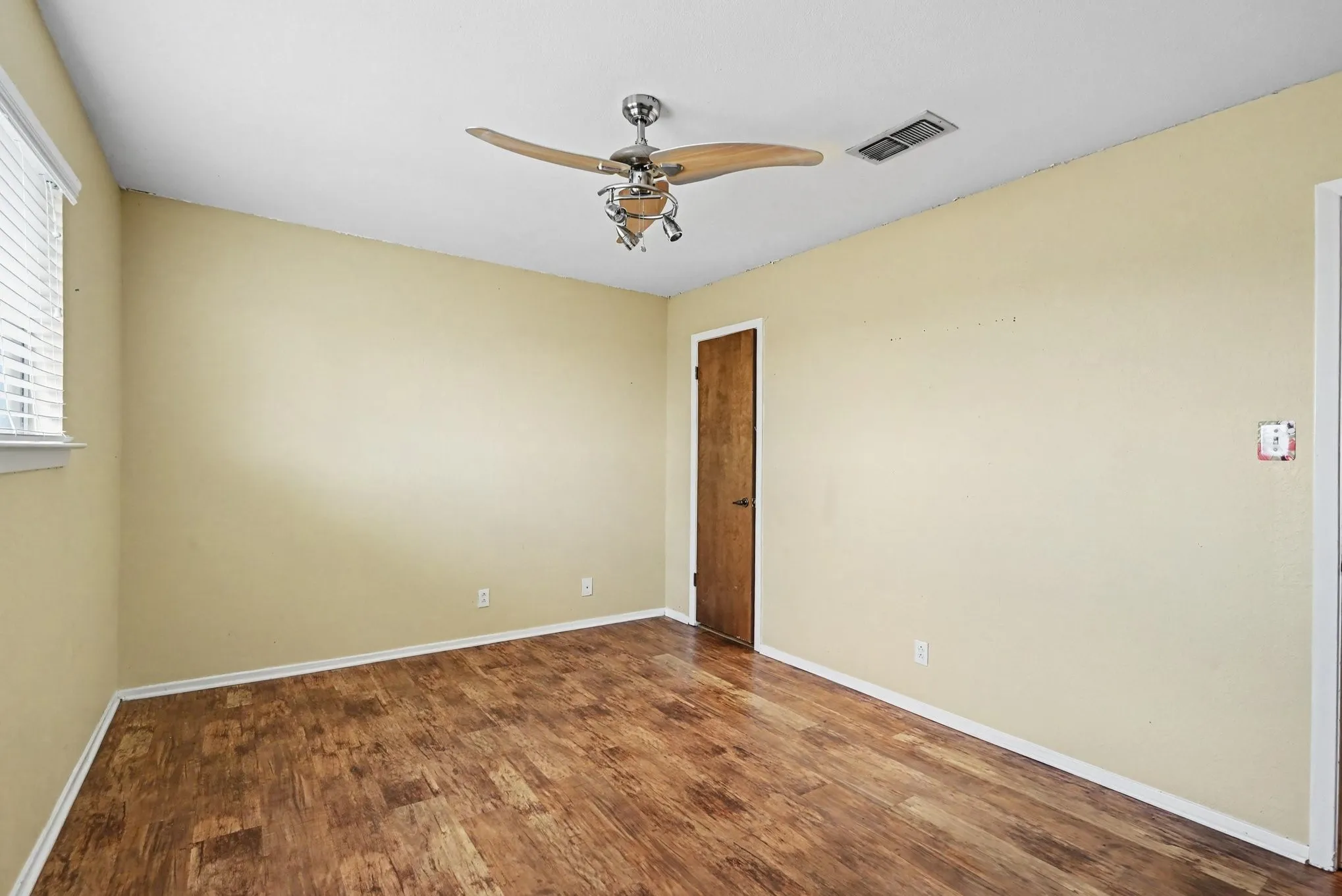 Wood-finish flooring, ceiling fan with integrated lighting, and window with horizontal blinds
