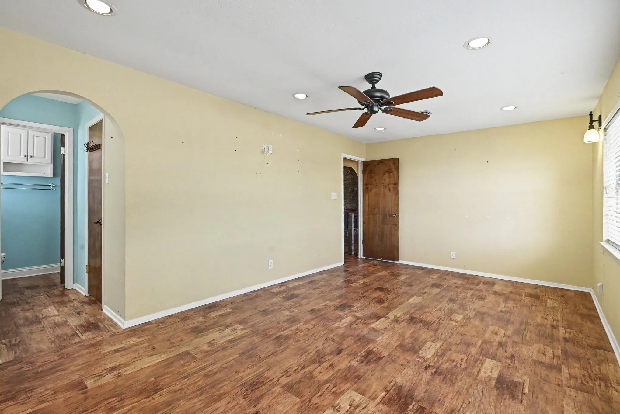 Vaulted ceiling featuring exposed beams, stone fireplace, wood-finish flooring, and multiple windows