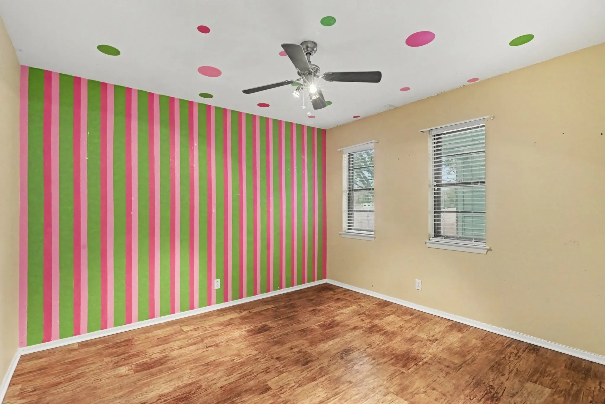 Wood-finish flooring, ceiling fan, and two windows with blinds