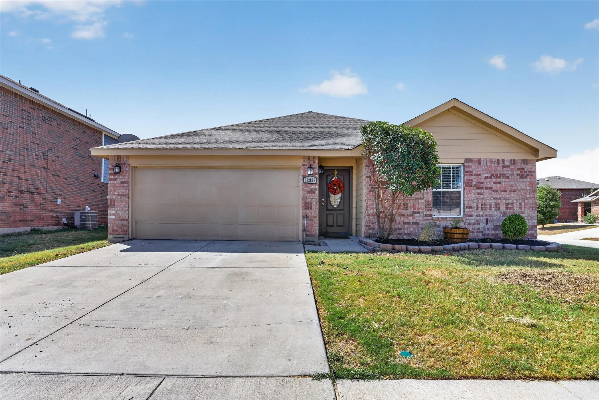 Brick and siding exterior with an attached garage, concrete driveway, and front landscaping