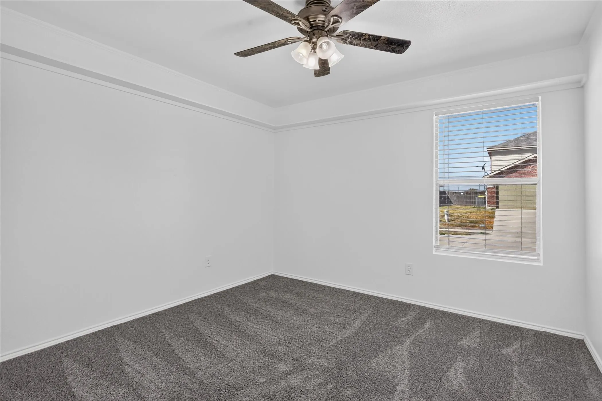 Recessed ceiling with crown molding, window with blinds, ceiling fan with integrated lighting, and gray carpet flooring
