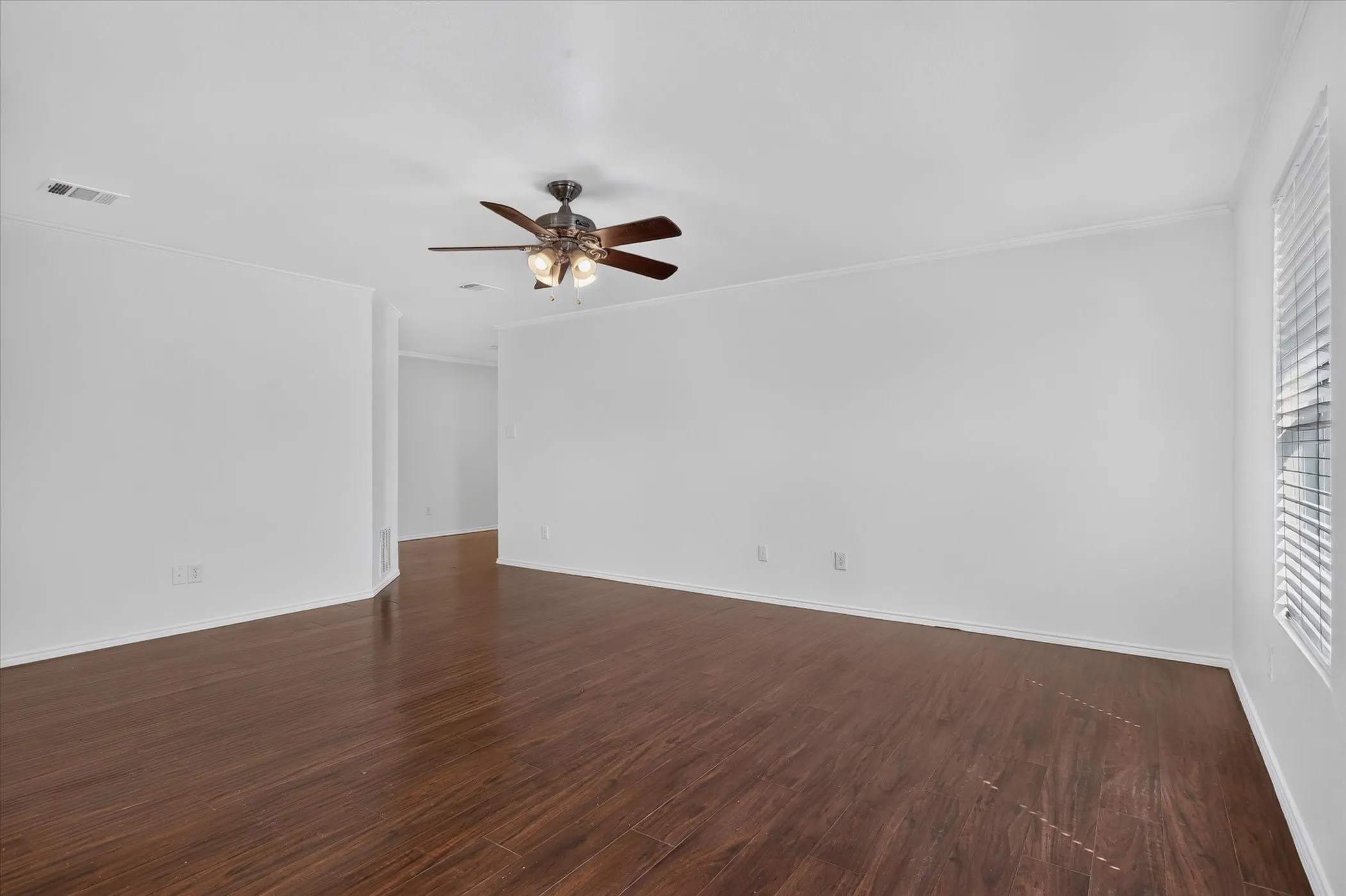 Wood-finish flooring, ceiling fan with integrated lighting, window with horizontal blinds, and white wall finishes