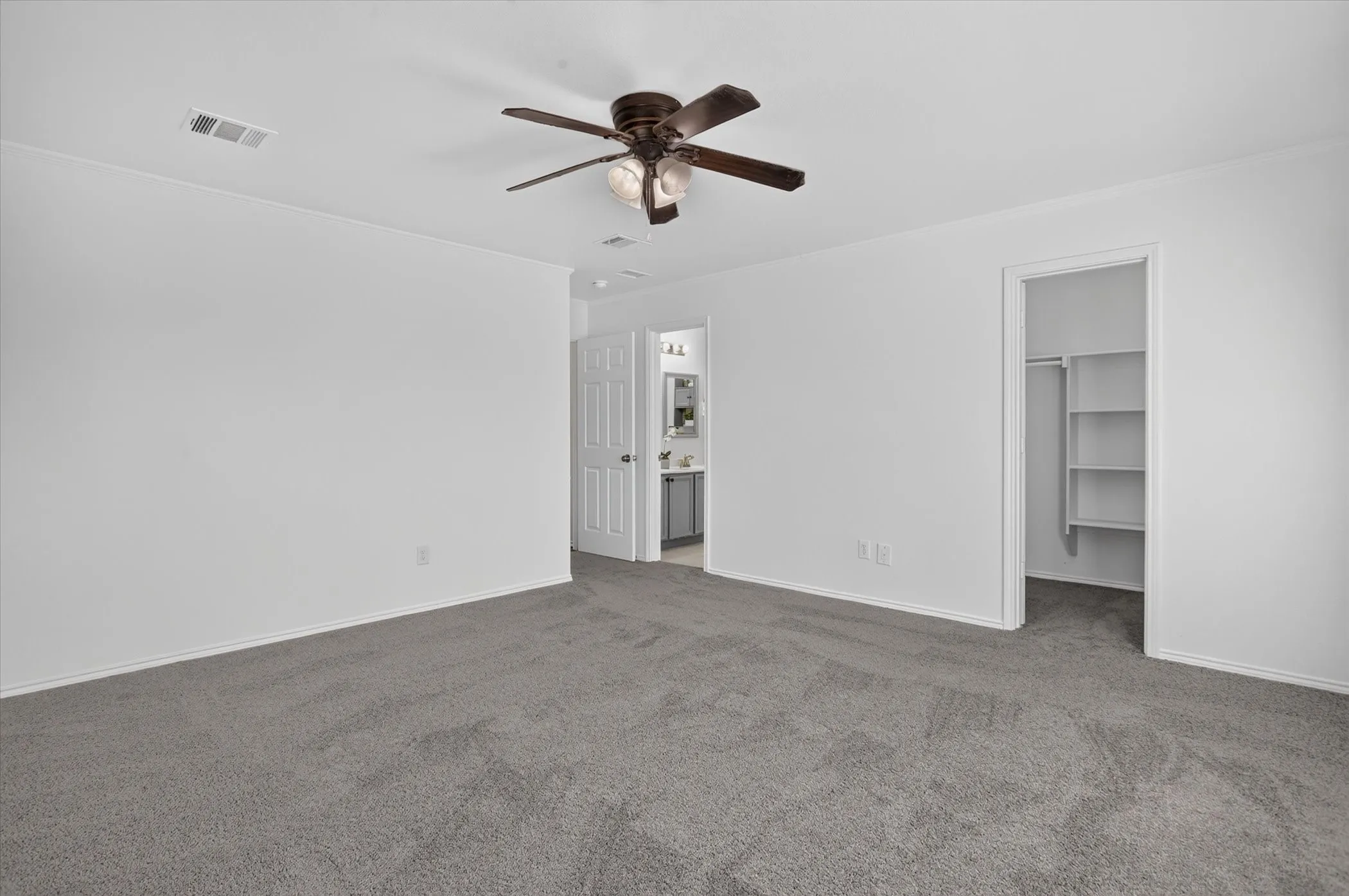 Spacious room with plush gray carpeting, a ceiling fan with light fixture, and white walls