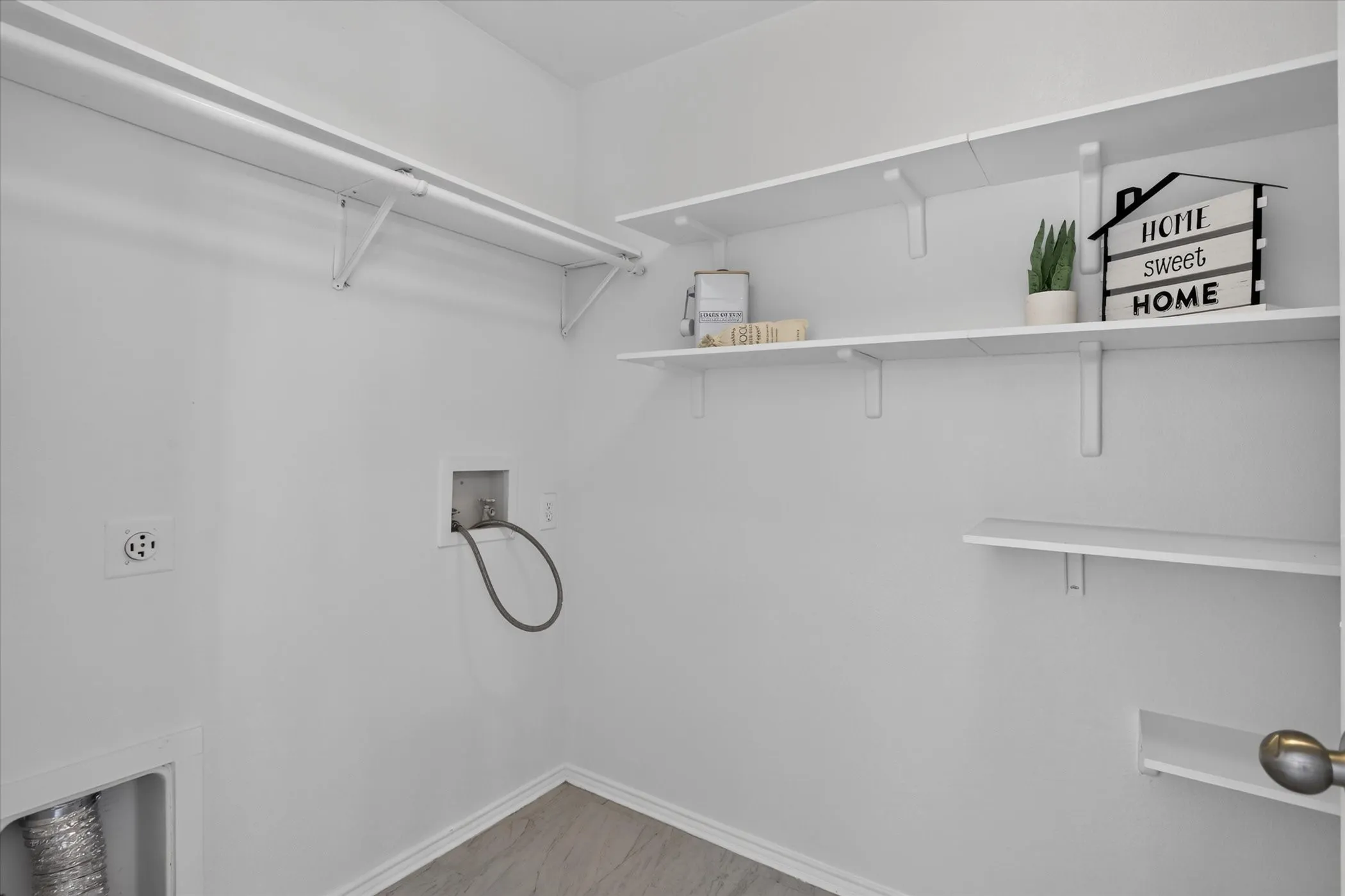 Laundry area with wood-finish flooring, white walls, and multiple storage shelves