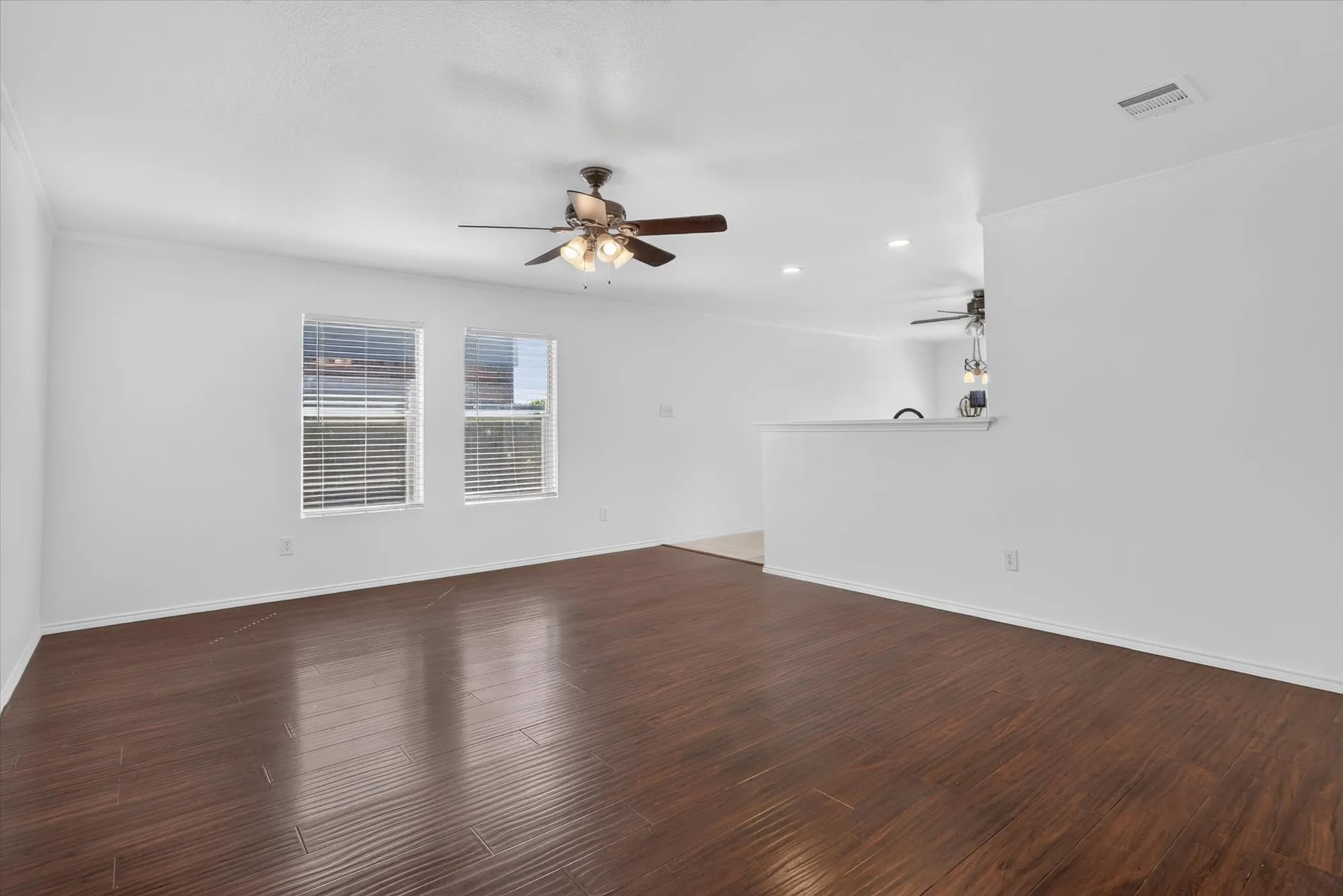 Wood-finish flooring, white walls, and a ceiling fan with integrated lighting