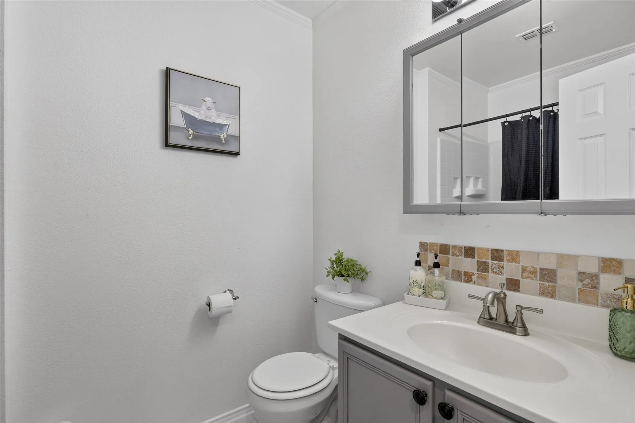 Vanity with integrated sink, mosaic tile backsplash, medicine cabinet, and toilet