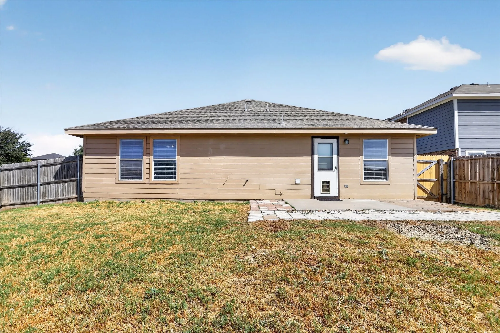 Rear exterior featuring horizontal siding, a composite shingle roof, a concrete patio, and a wood privacy fence