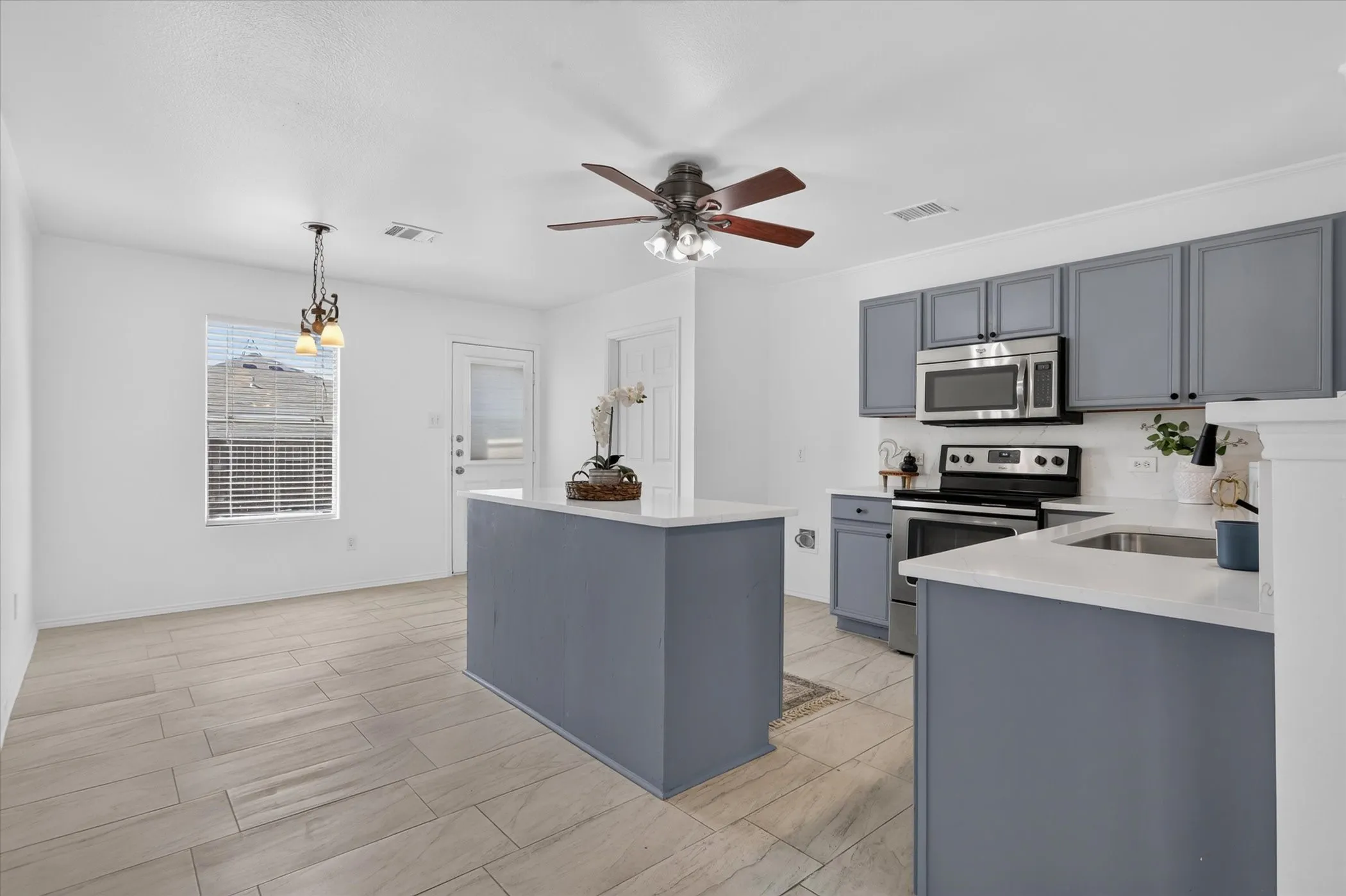 Kitchen featuring light wood-finish flooring, white countertops, gray cabinetry, and stainless steel appliances