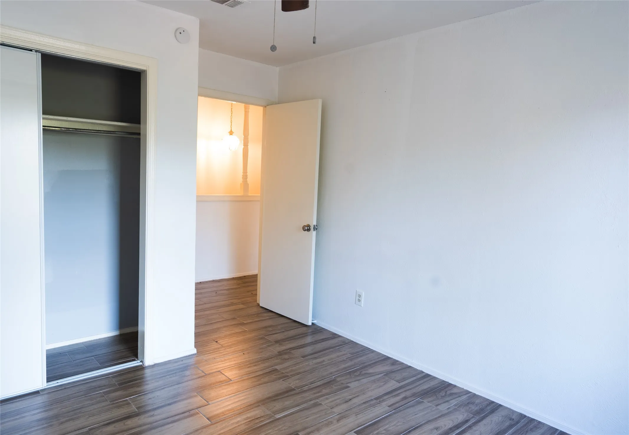 Wood-finish flooring, white walls, and a ceiling fan