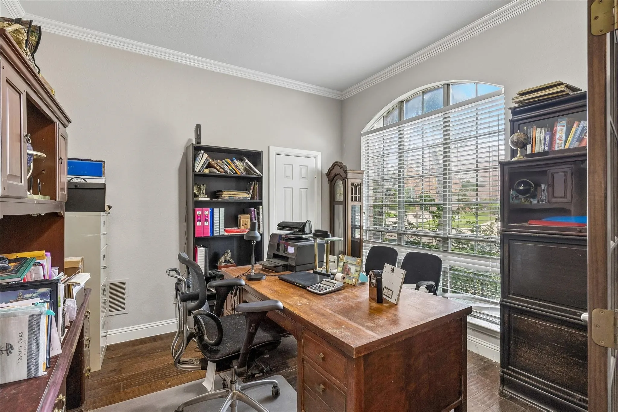 Hardwood-finish flooring, built-in shelving, crown molding, and an arched window
