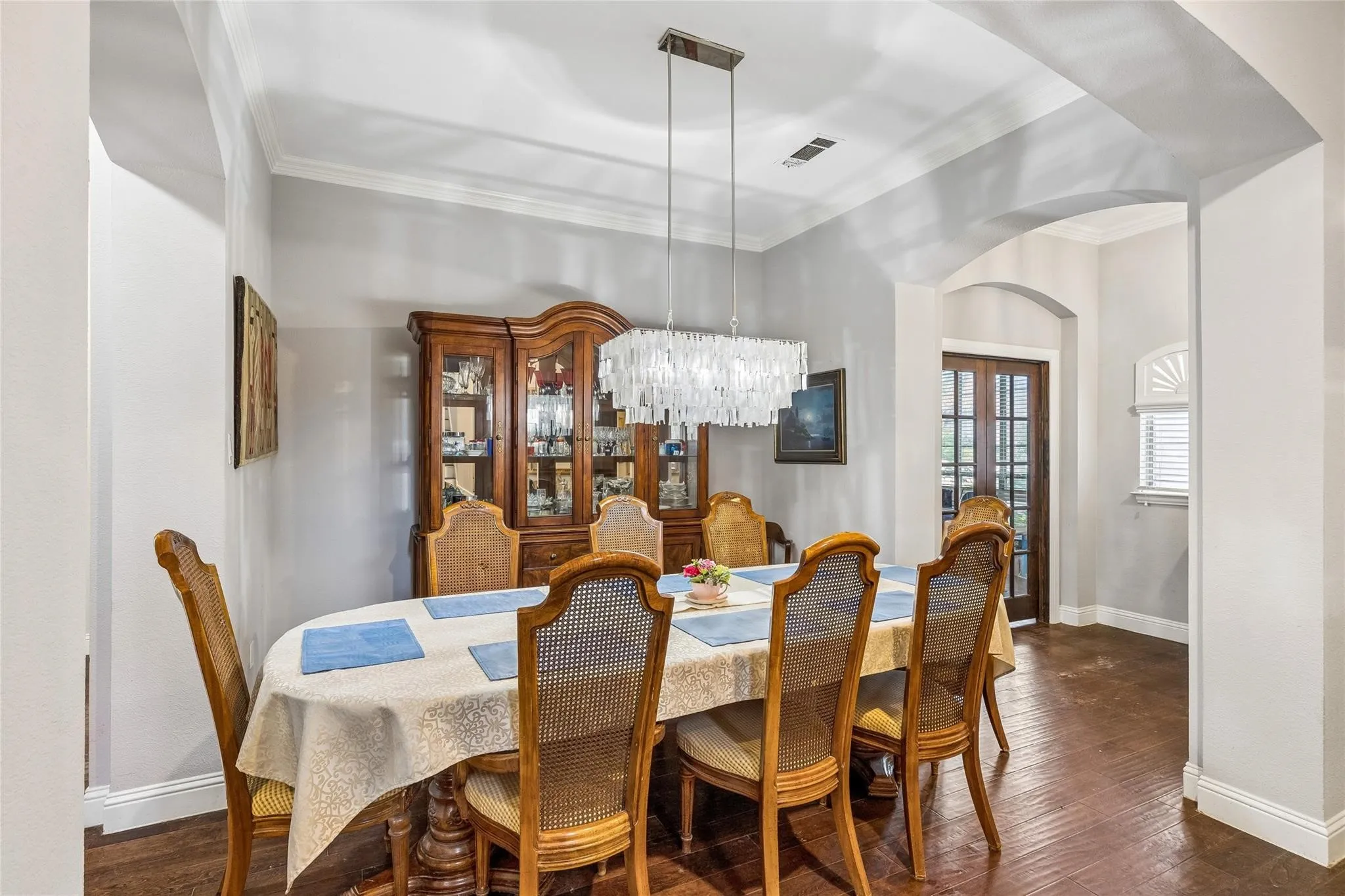 Wood-finish flooring, crown molding, and an arched entry