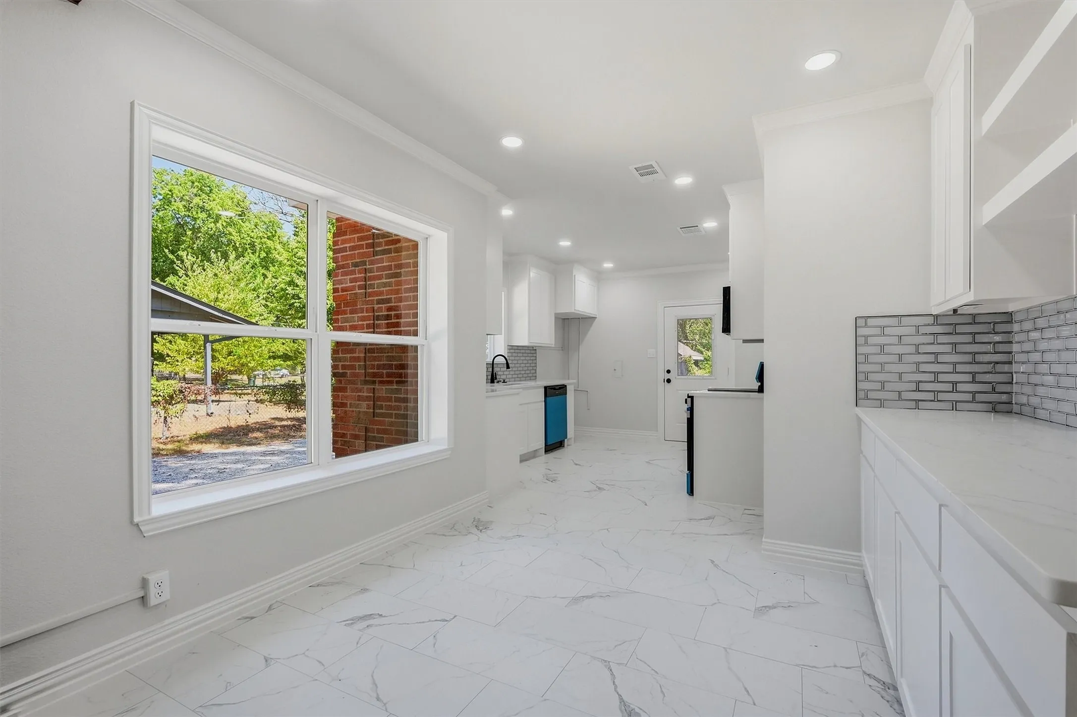 White shaker cabinetry, recessed lighting, white countertops, subway tile backsplash, and large format tile flooring