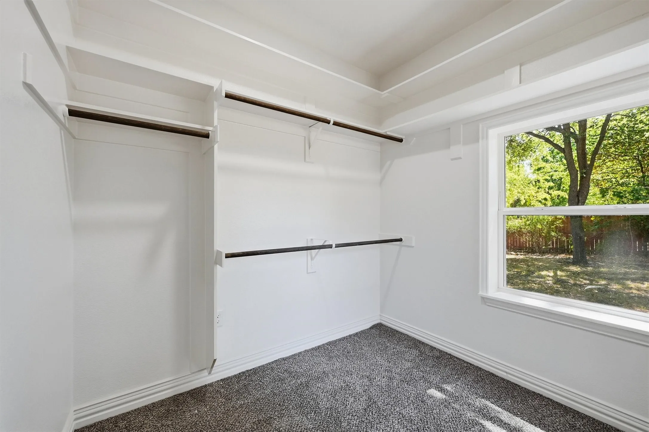 Walk-in closet with built-in shelving, hanging rods, and a large window