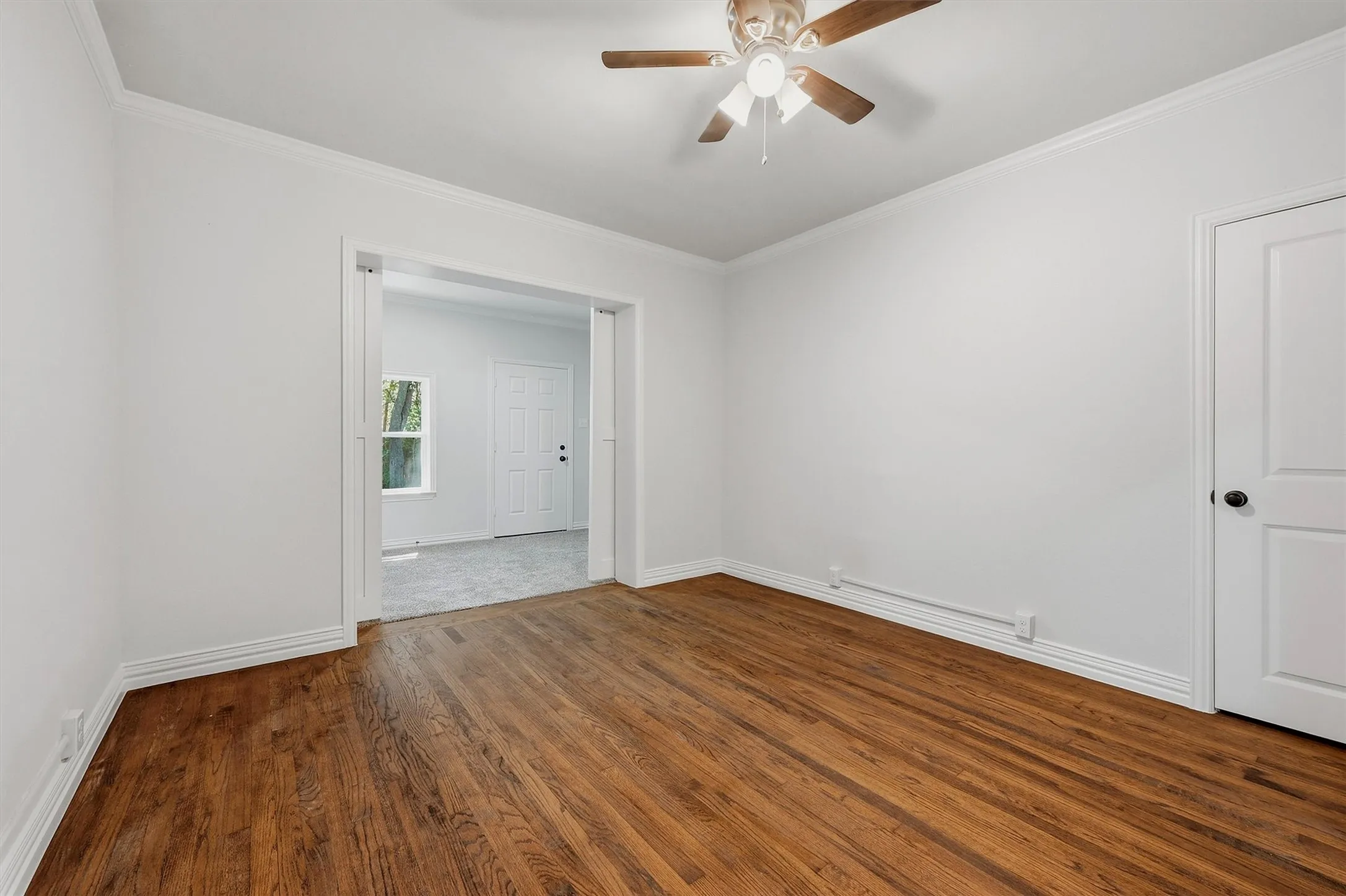 Rich wood-finish flooring with crisp white crown molding and baseboards