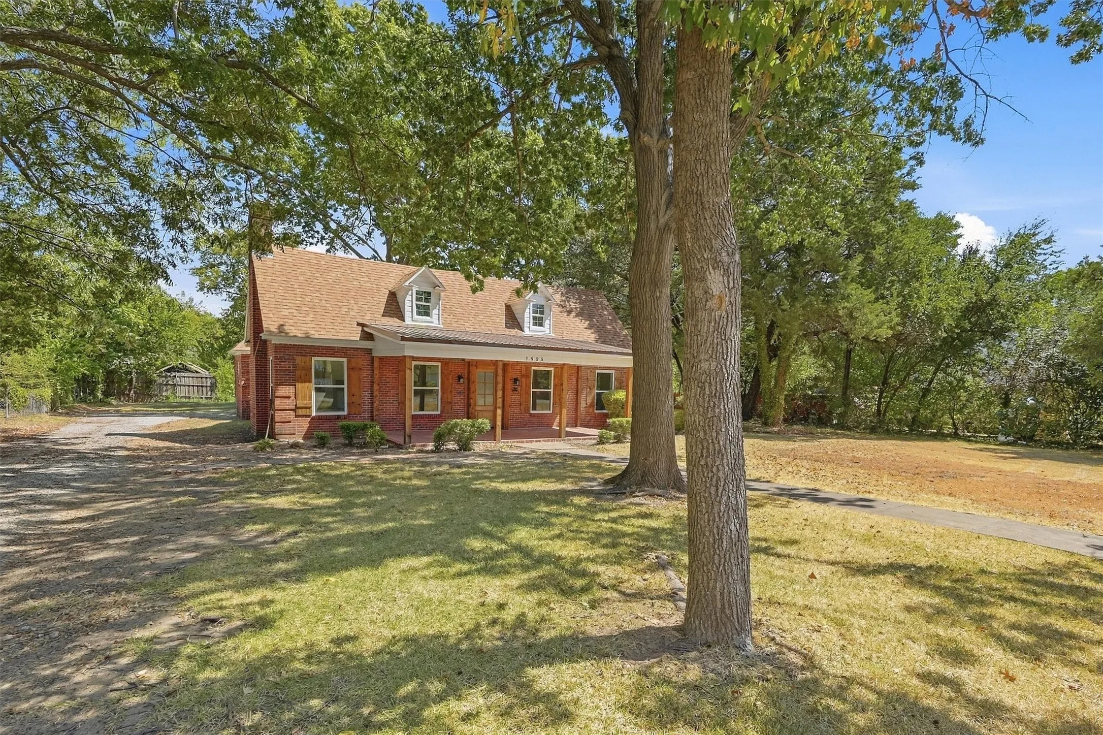 Brick exterior with a shingle roof, front porch, and multiple dormer windows