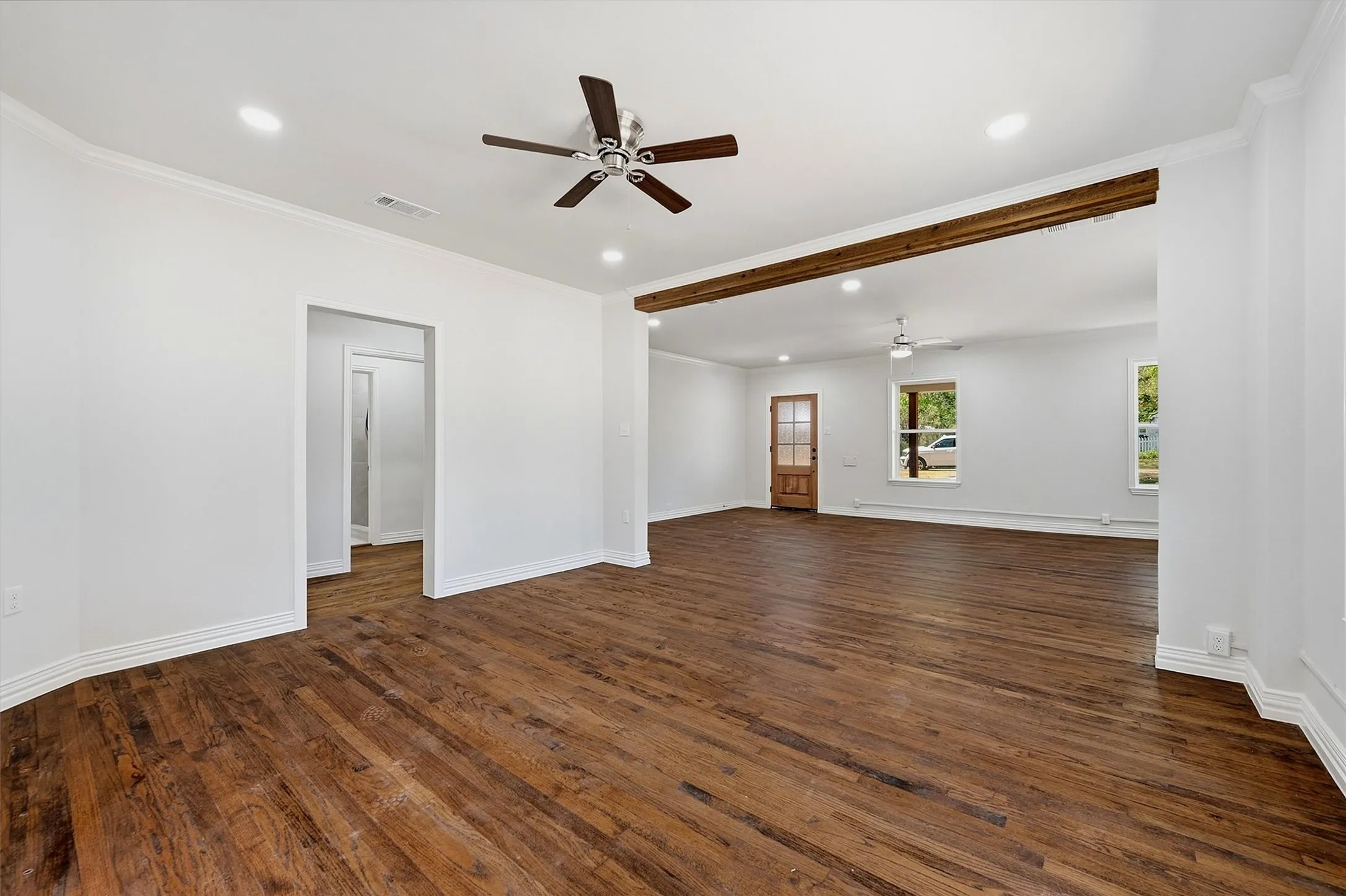 Wood-finish flooring, recessed lighting, ceiling fans, crown molding, and exposed wood beam