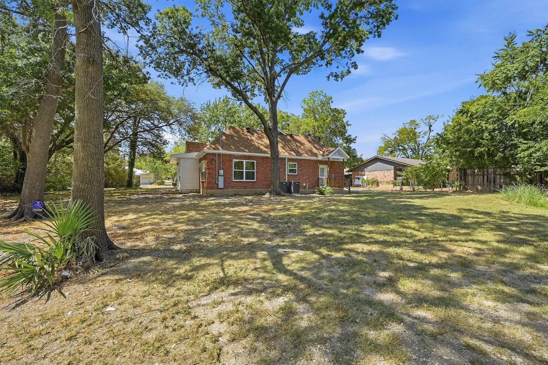 Expansive backyard with mature trees and a red brick exterior
