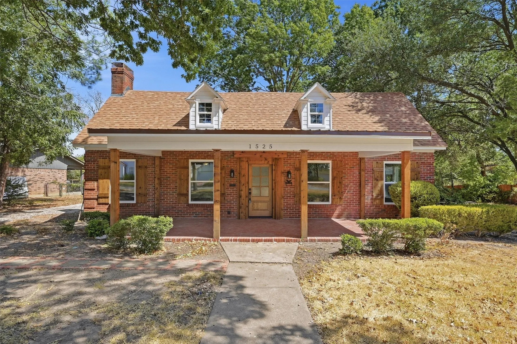 Brick exterior with dormer windows and a covered front porch featuring wood support columns