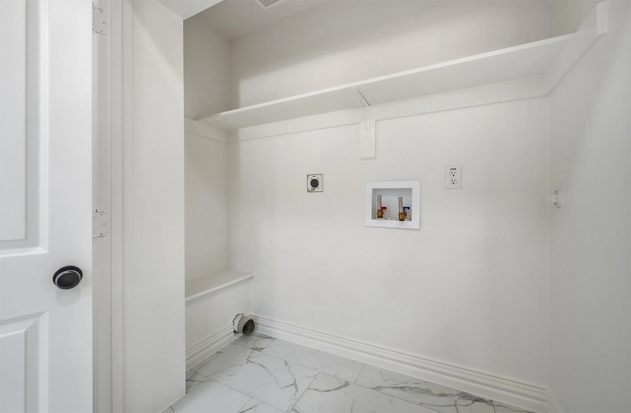 Laundry area featuring white walls, white tile flooring, and built-in shelving