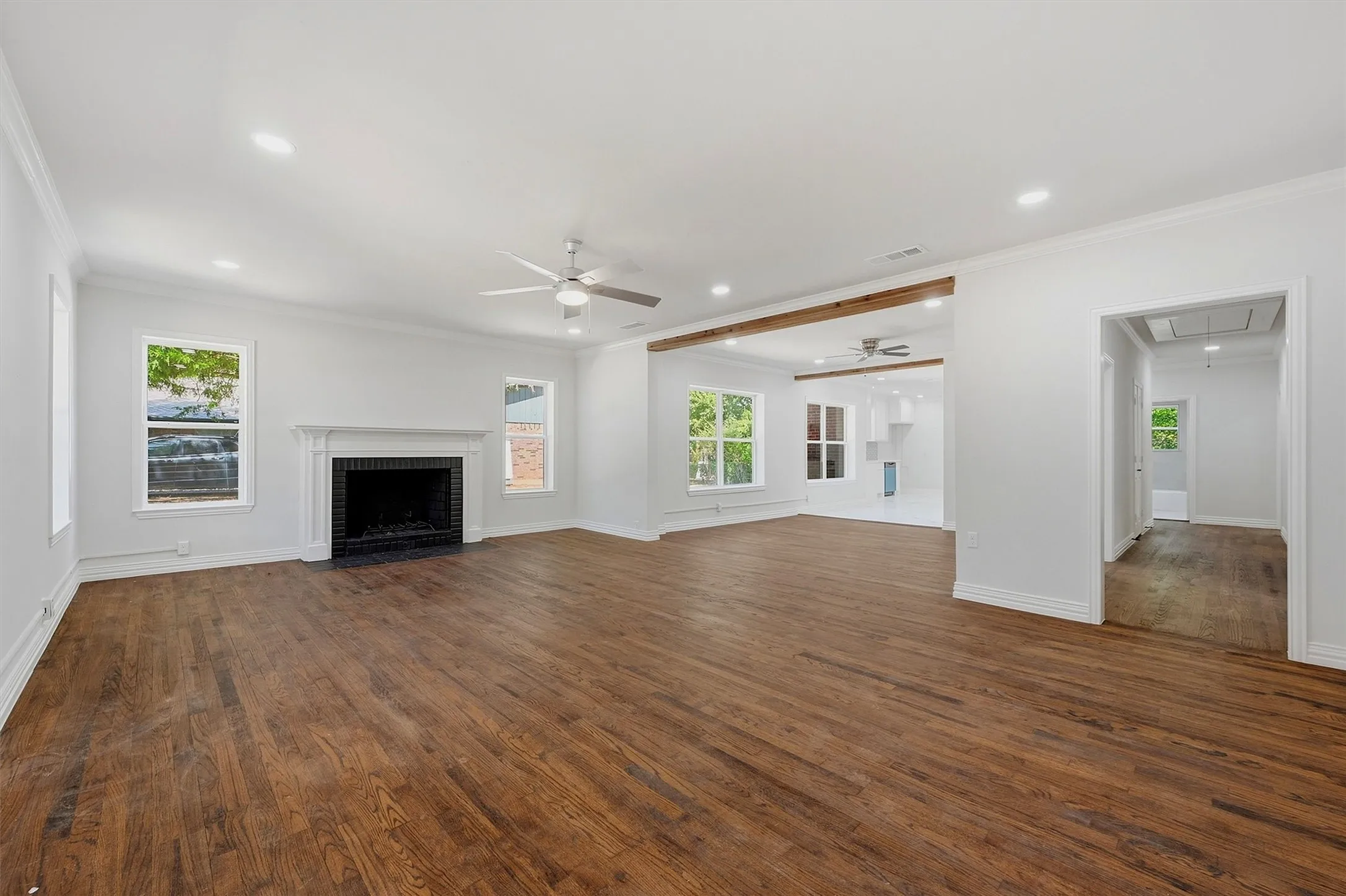 Expansive living area featuring wood-finish flooring, a white mantel fireplace, and recessed lighting