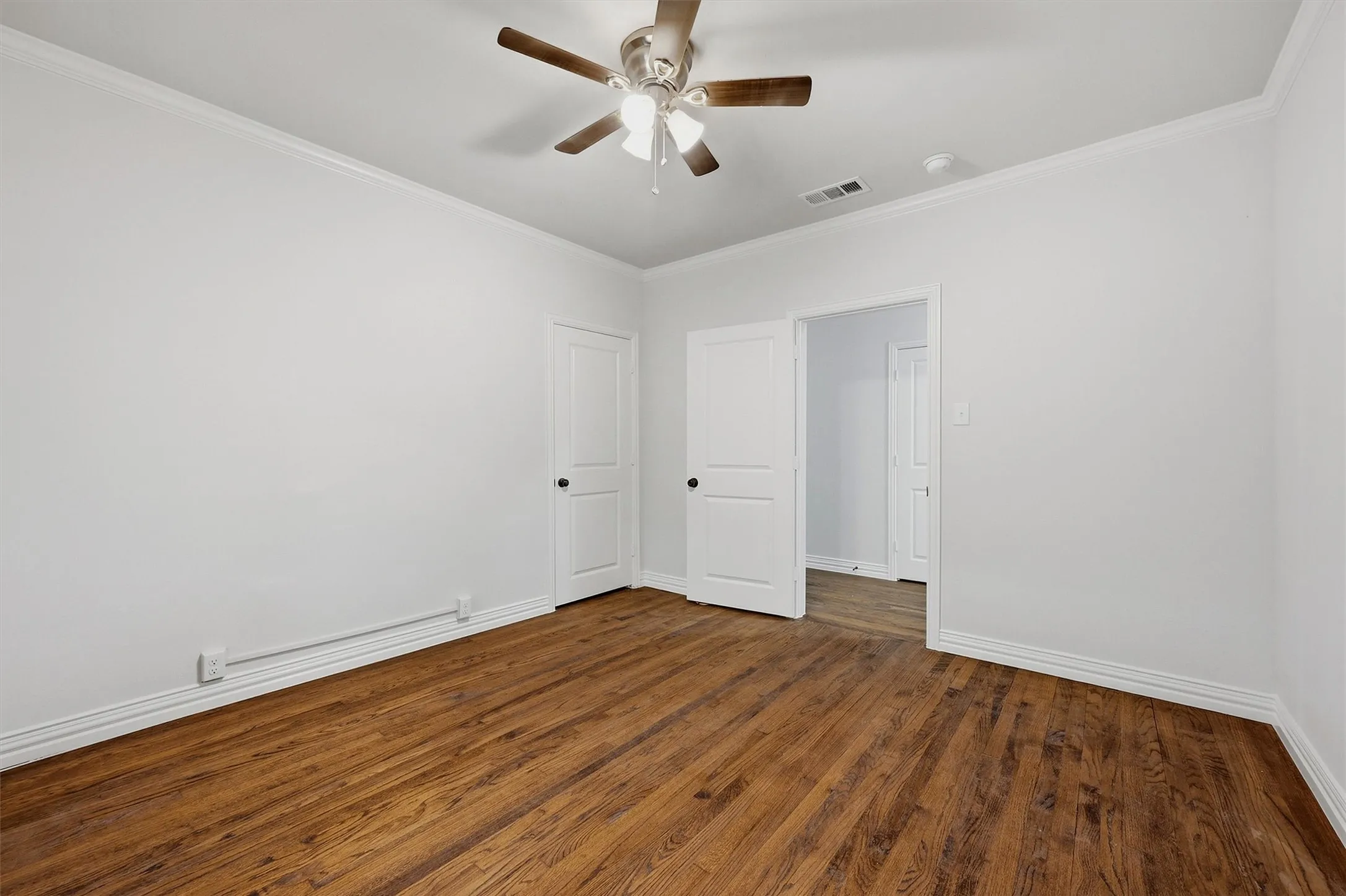 Wood-finish flooring, white walls, white trim, and a ceiling fan with light fixture
