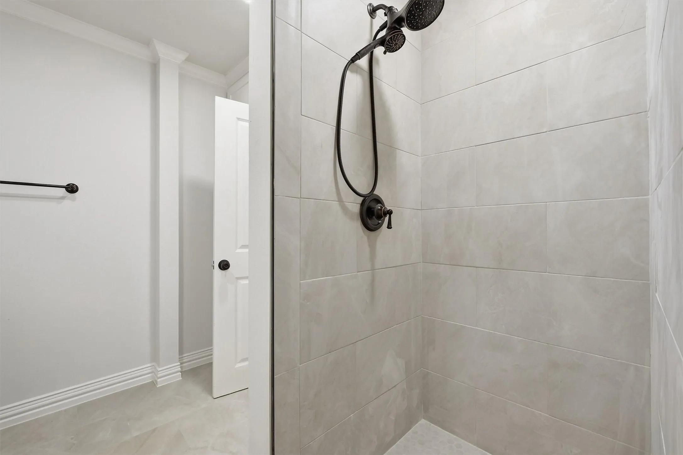 Walk-in shower with textured wall tile and bronze-finish fixtures