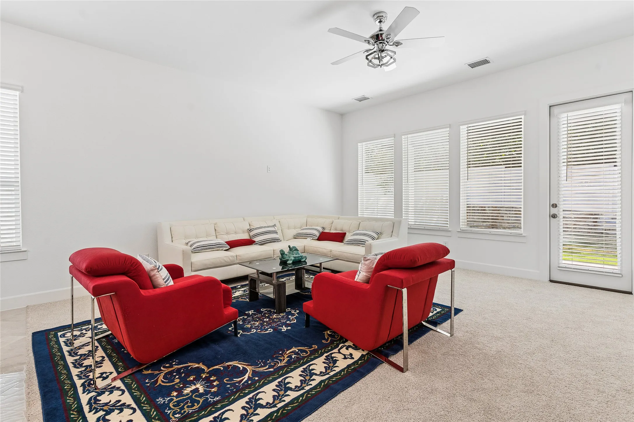 Recessed lighting, ceiling fan, multiple windows with blinds, and a glass-paneled door