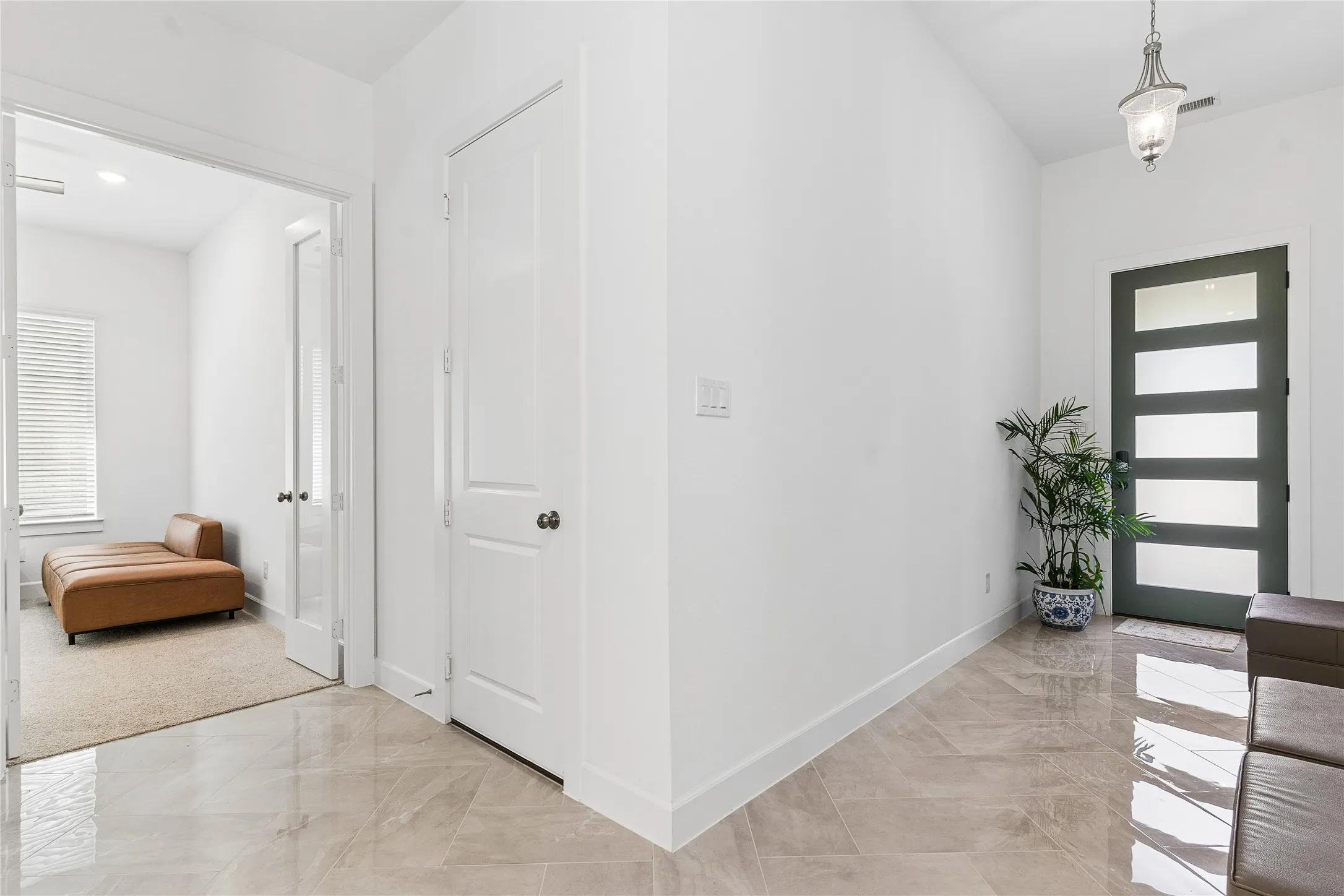 Porcelain tile flooring throughout the entry, modern panel door with opaque glass inserts, recessed lighting, and a frosted glass panel door