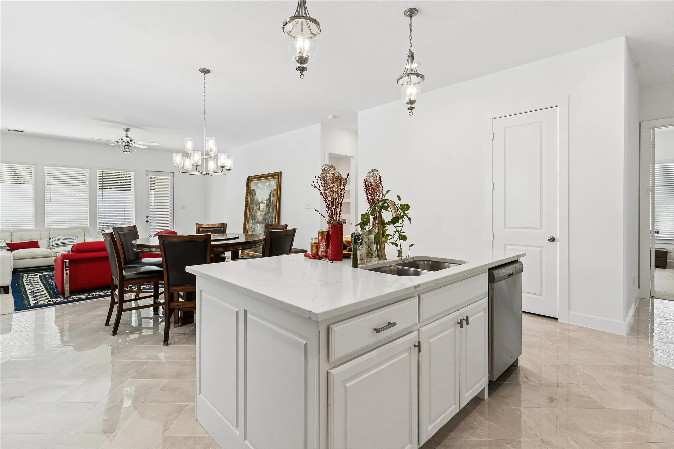 Kitchen island with built-in stainless steel sink, white cabinetry, and light-colored countertop