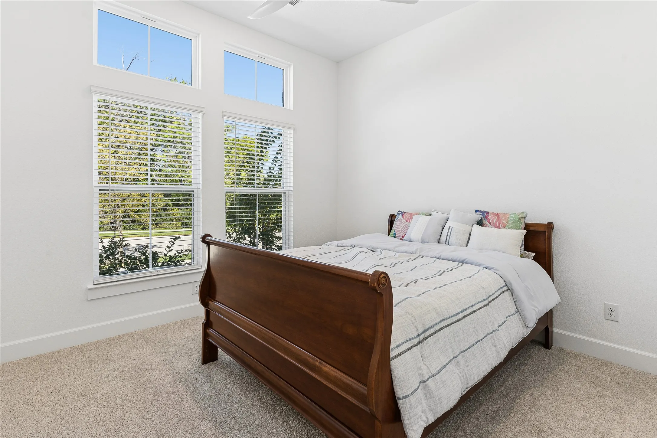 Spacious interior with high ceilings, light-toned carpeting, and white walls