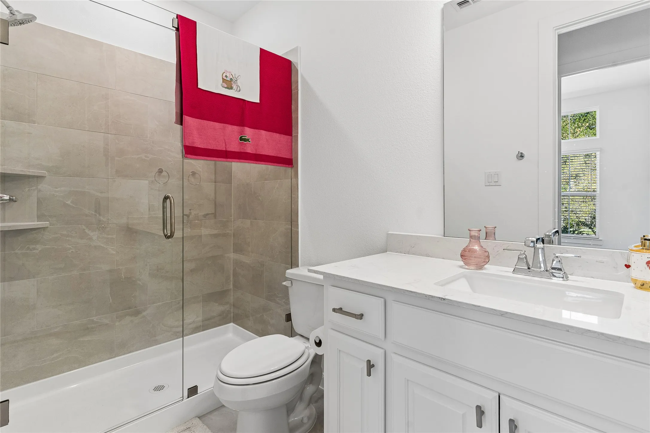 Glass-enclosed shower with tiled surround, built-in shelving, and rain showerhead