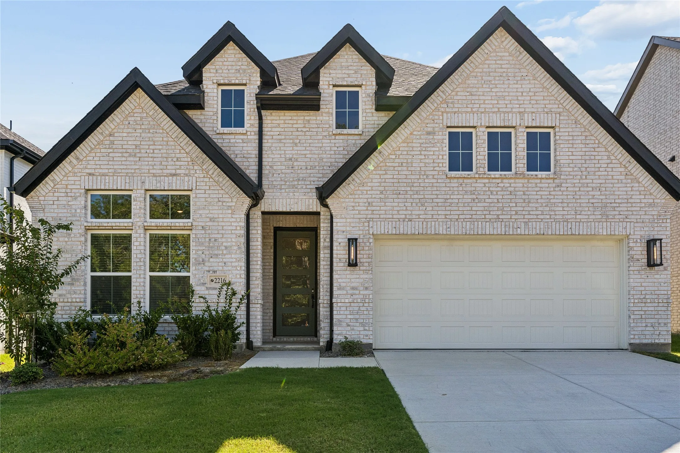 Light brick exterior with black trim, multiple gables, and a two-car garage