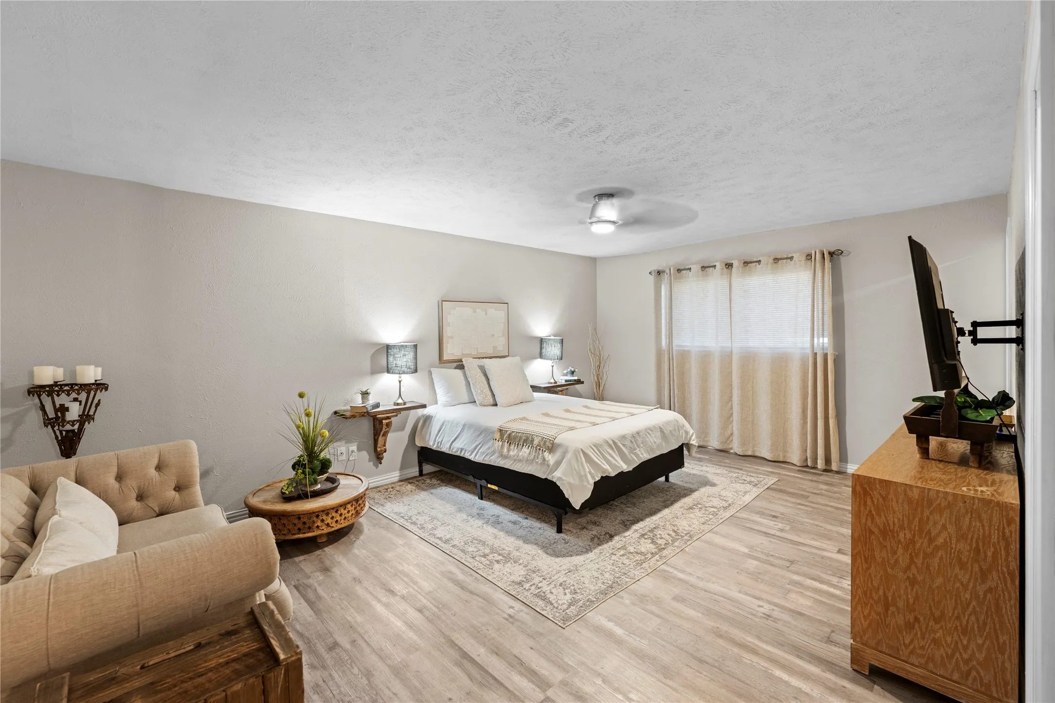 Spacious room featuring wood-finish flooring, a ceiling fan with integrated lighting, and neutral wall tones