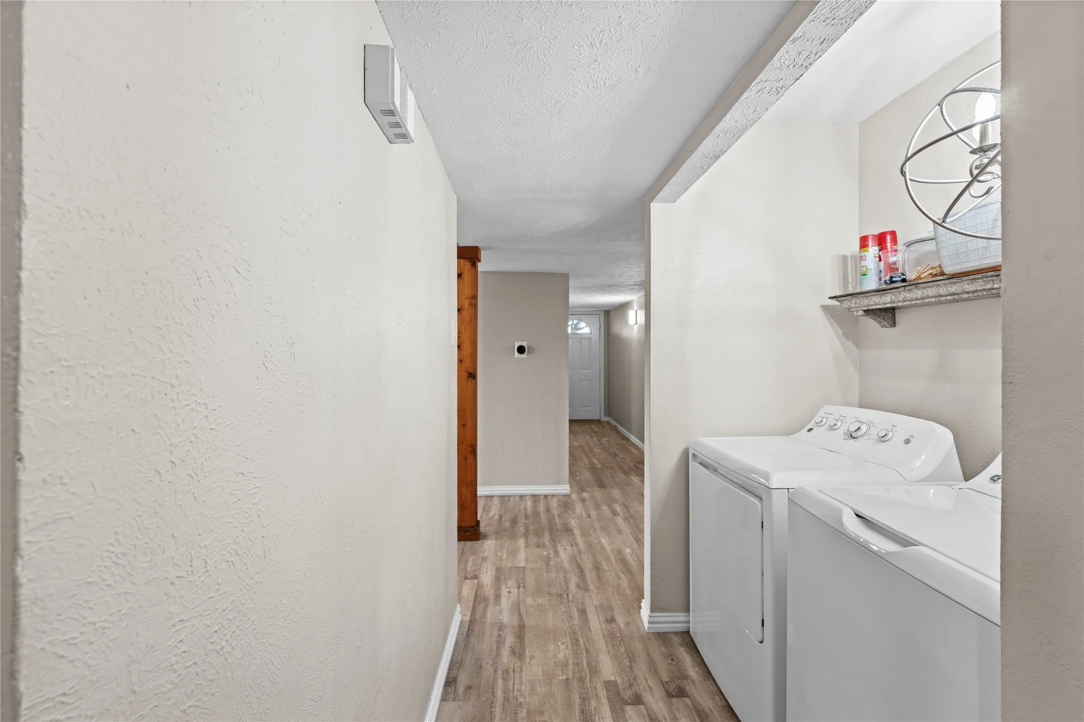 Laundry area with a built-in shelf and wood-finish flooring