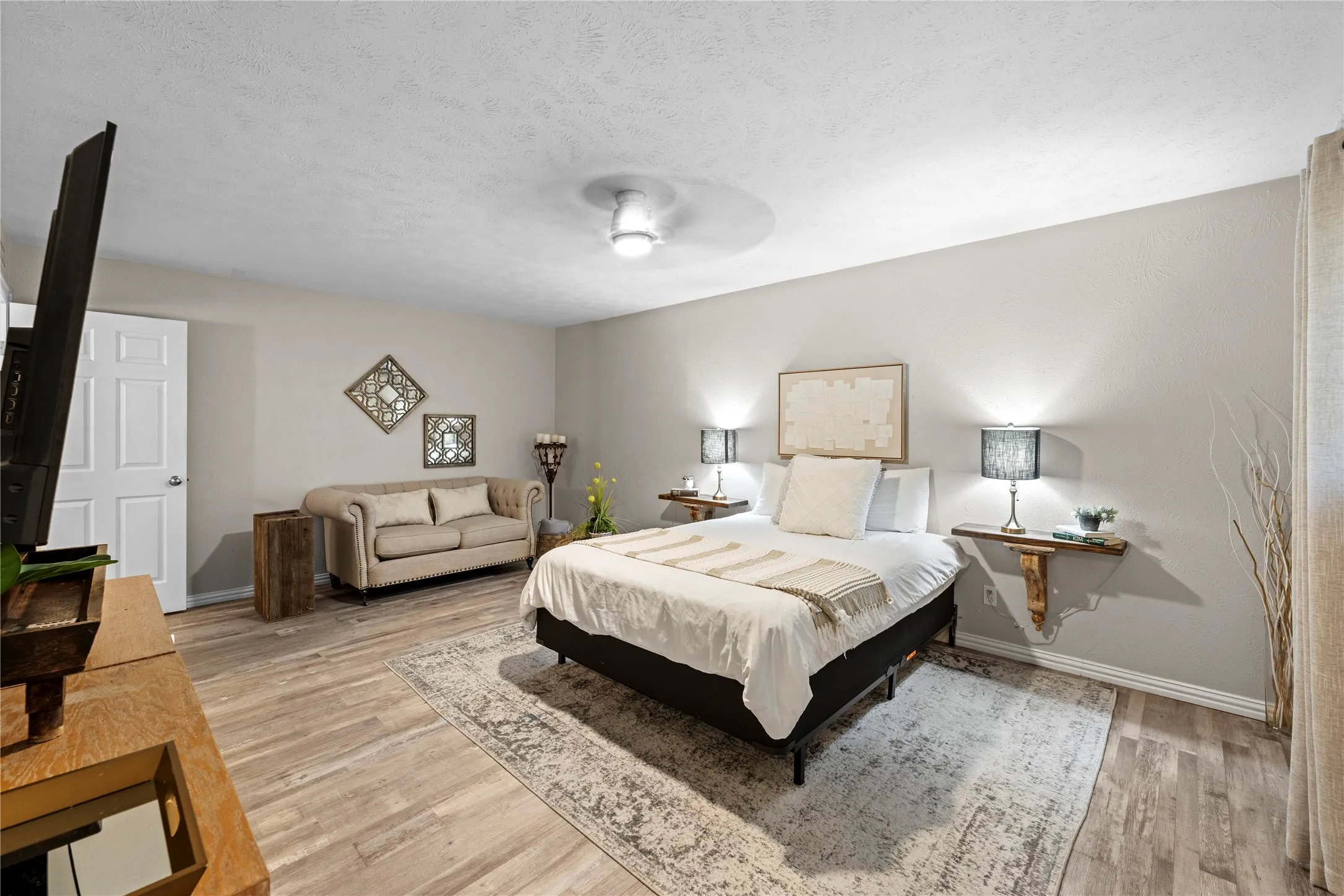Neutral wall finishes, wood-finish flooring, ceiling fan, and paneled interior door
