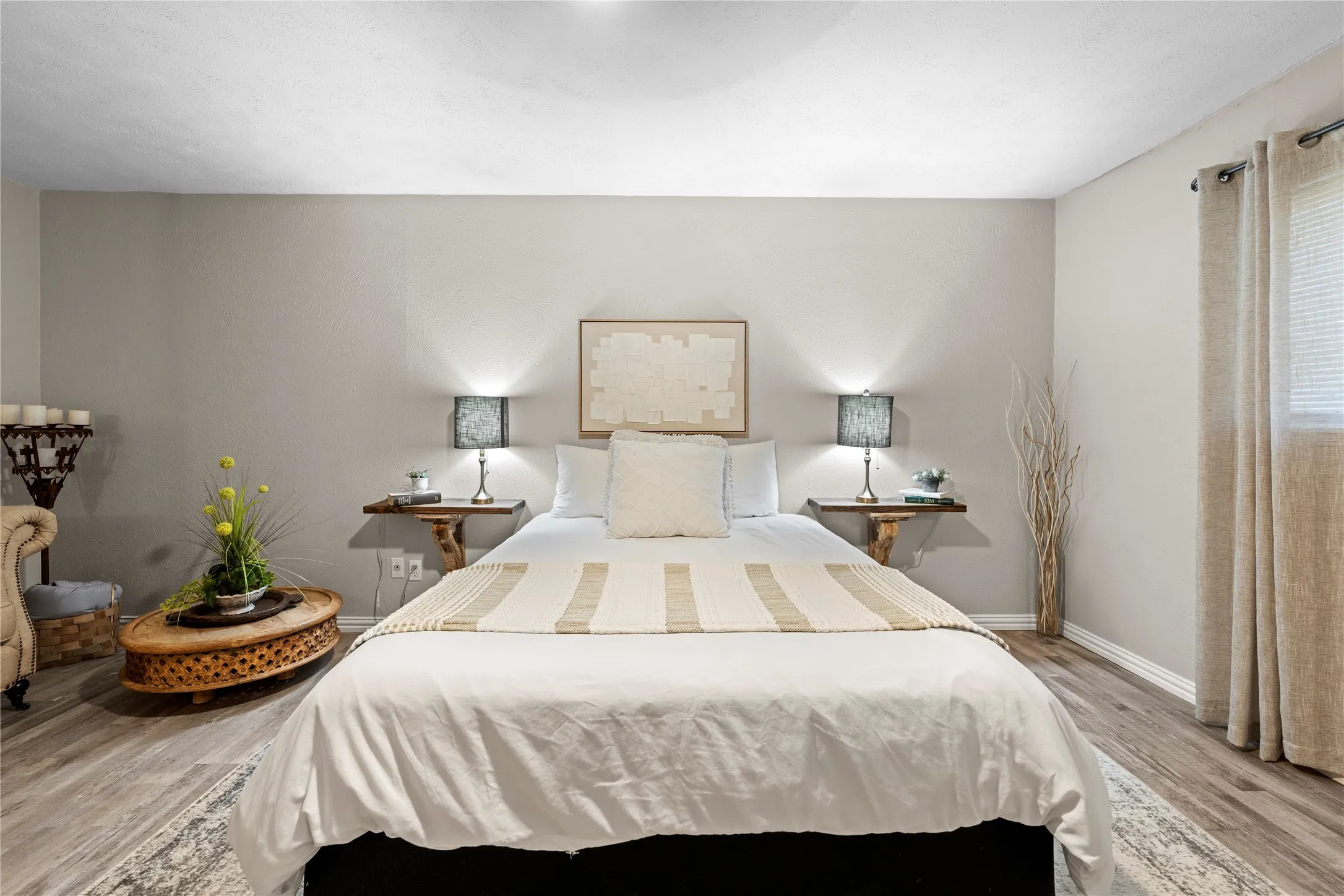 Neutral wall tones, wood-finish flooring, recessed ceiling lighting, window with blinds and drapes, and wall-mounted shelving