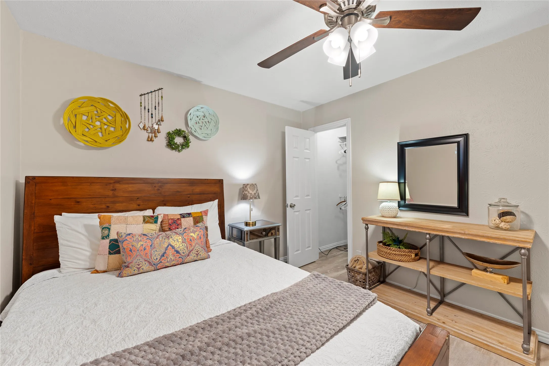 Wood-finish flooring, ceiling fan with integrated lighting, and a white interior door