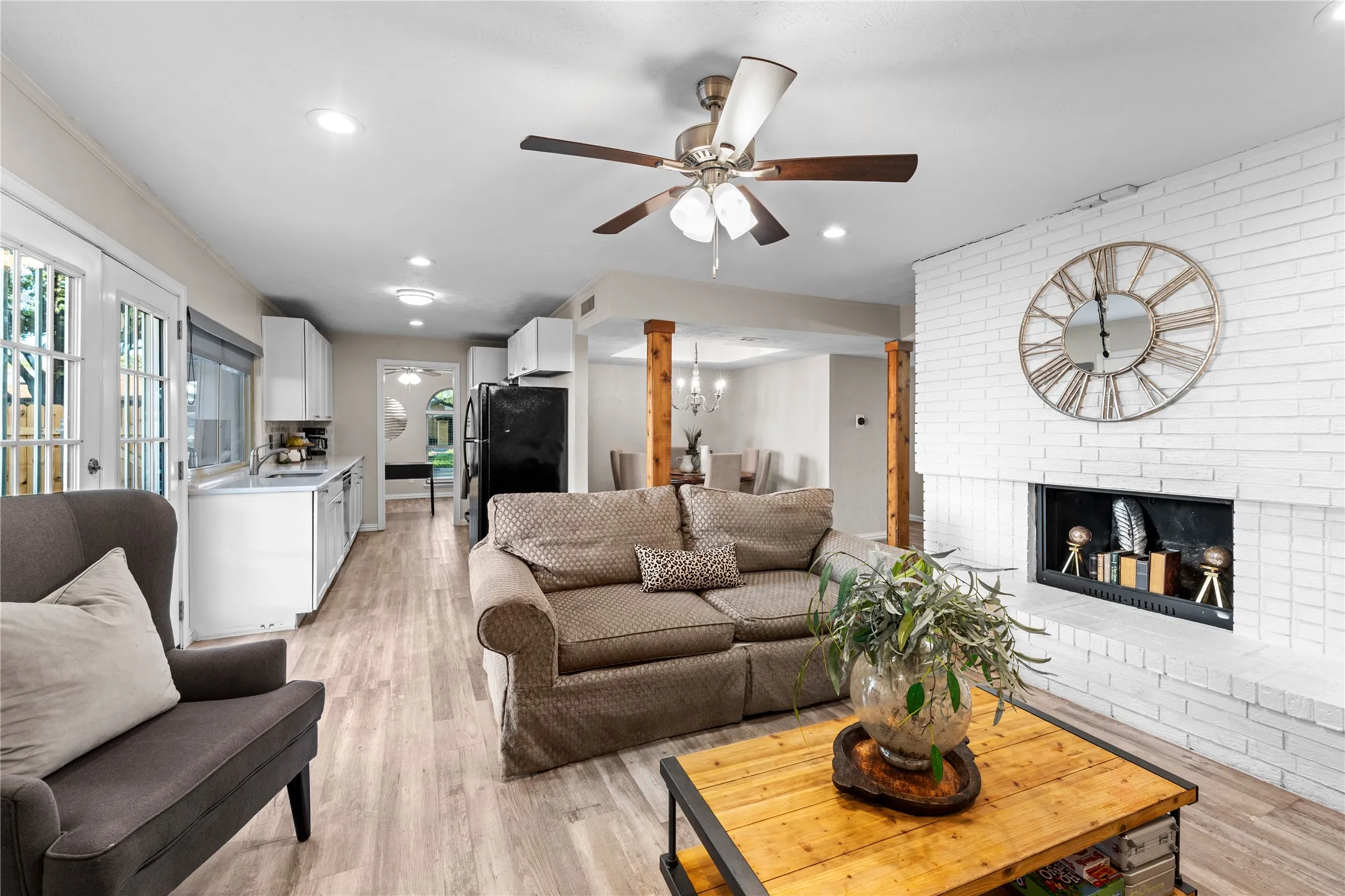 Recessed lighting, wood-finish flooring, white brick fireplace, ceiling fan, and French doors