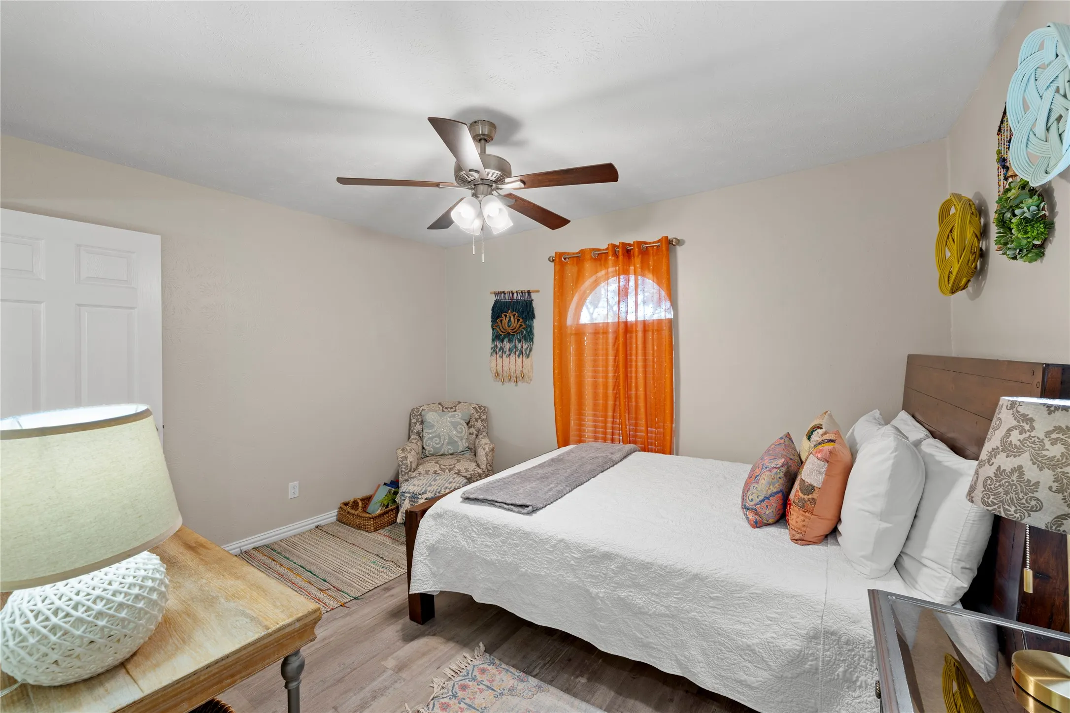 Wood-finish flooring throughout, ceiling fan with light fixture, and arched window