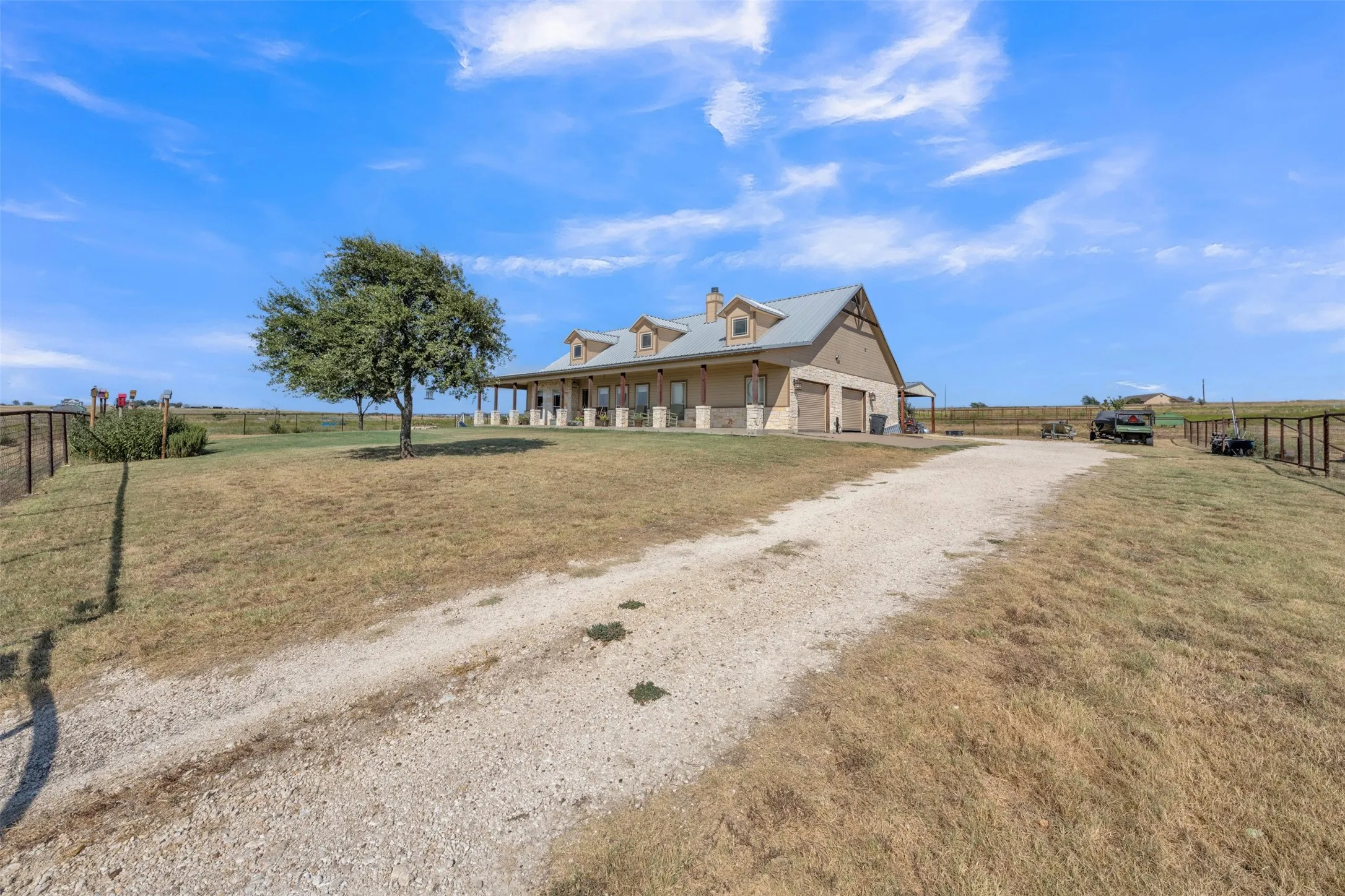 Stone and stucco exterior, covered front porch, dormer windows, metal roof, and attached two-car garage