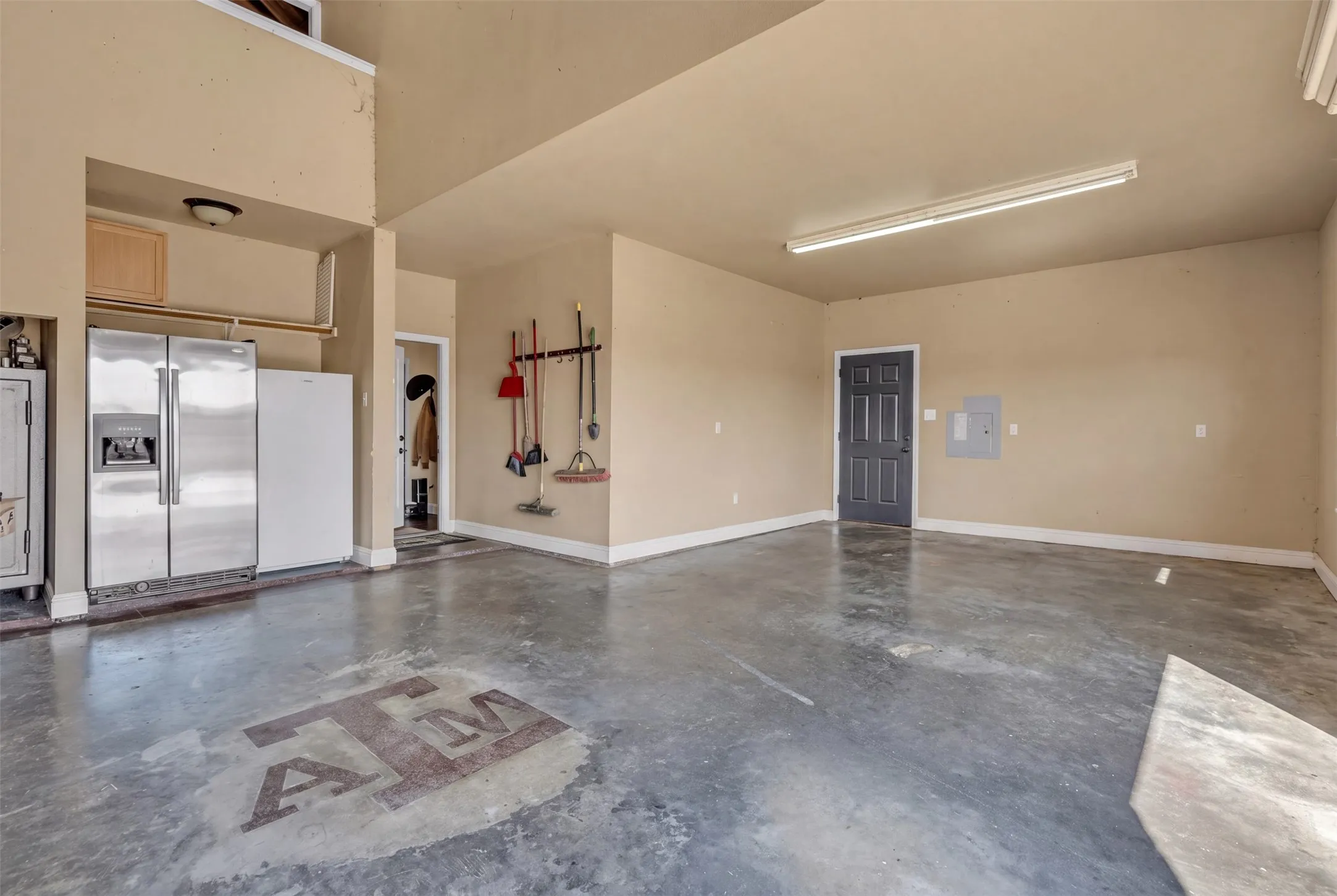 Expansive concrete flooring with a distinct graphic, high ceilings, and recessed lighting