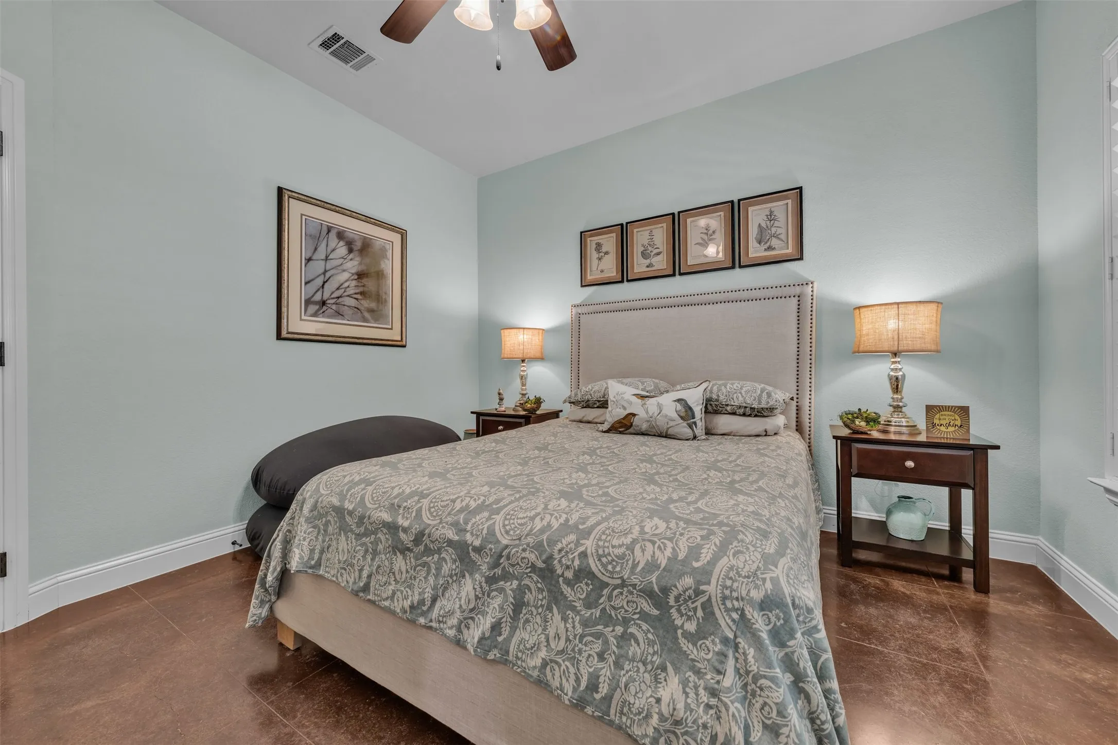 Concrete-finish flooring, ceiling fan, and window with plantation shutters
