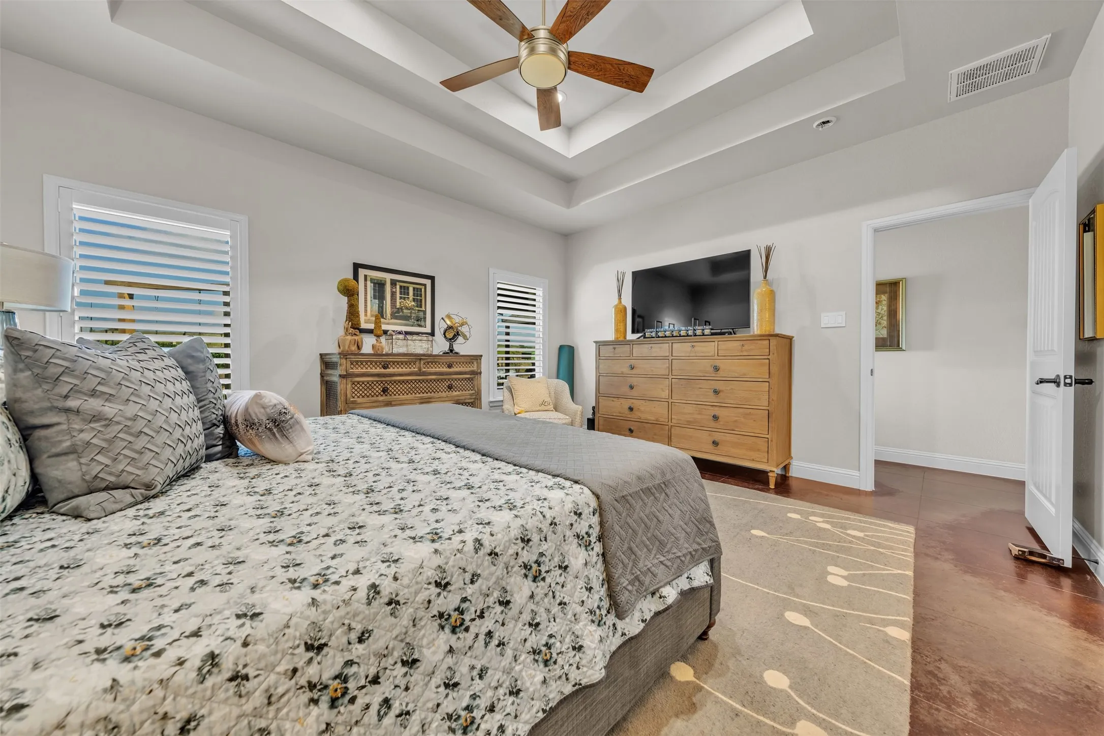 Tray ceiling with a ceiling fan, wood-finish flooring, and white interior doors