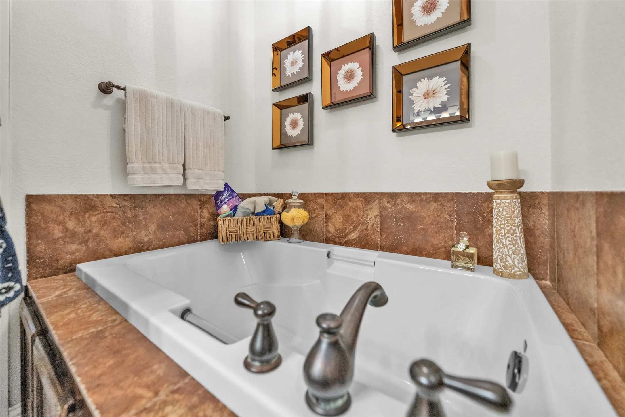 Built-in soaking tub with bronze-tone fixtures and a surrounding tile surface