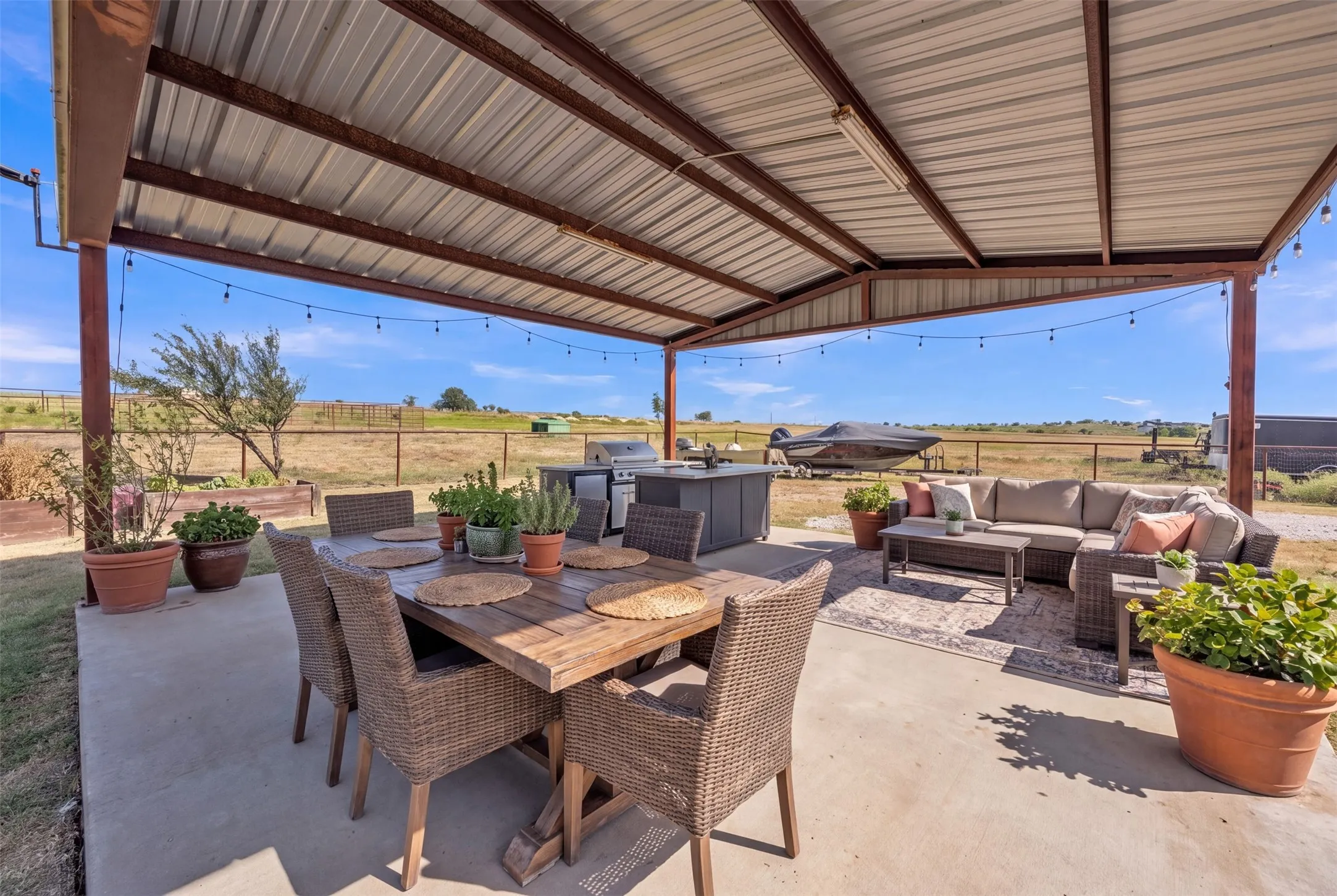 Expansive covered patio with a metal roof structure, concrete flooring, and an integrated outdoor kitchen space