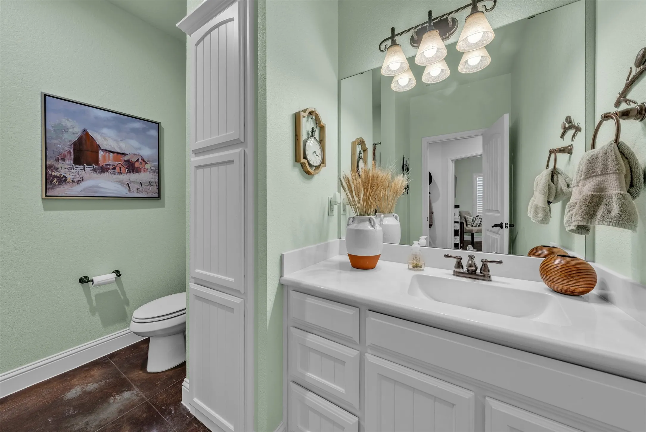 White vanity with an integrated sink and bronze-finish faucet, under a large mirror with a five-light fixture