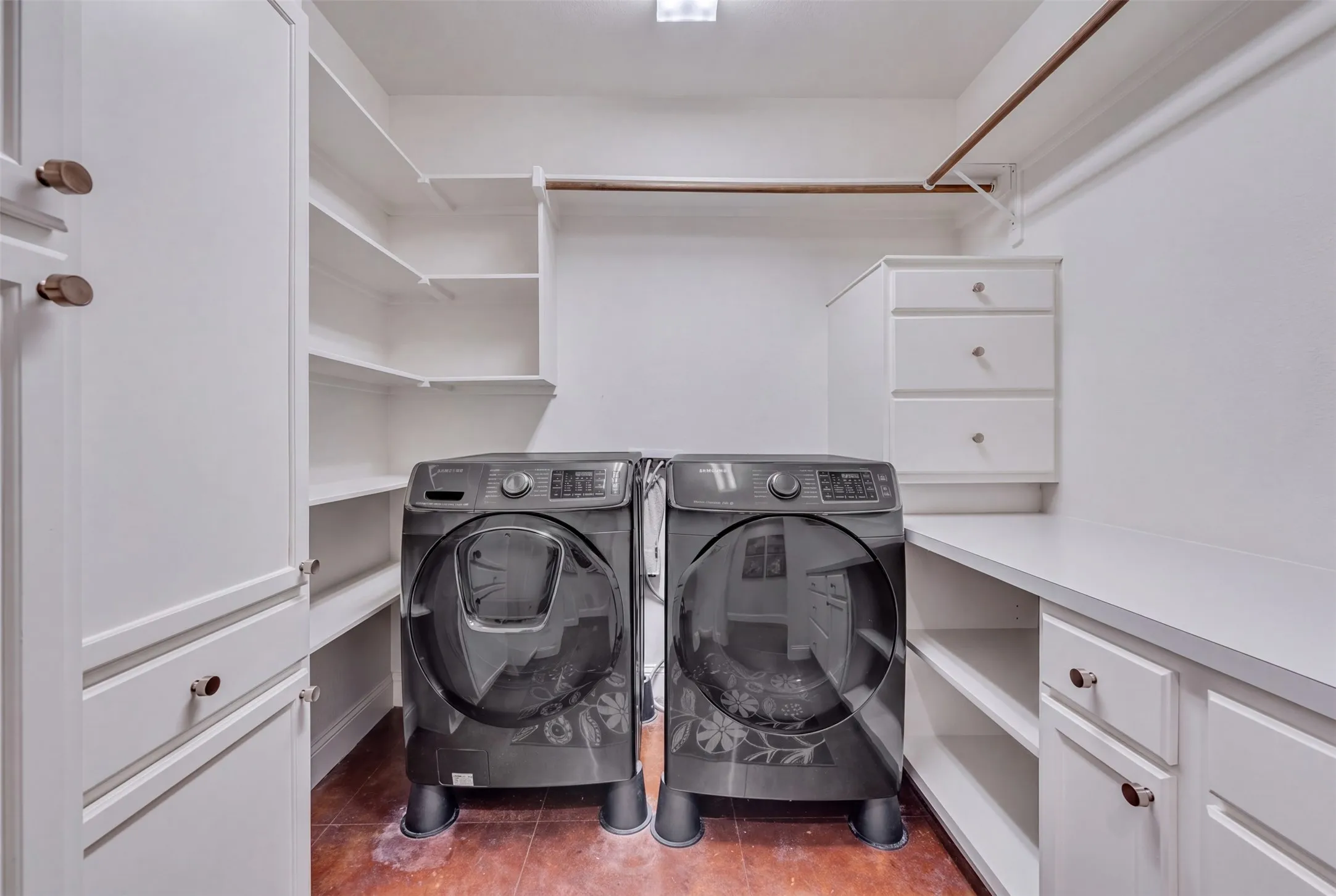 Laundry area featuring built-in cabinetry, shelving, and a hanging rod