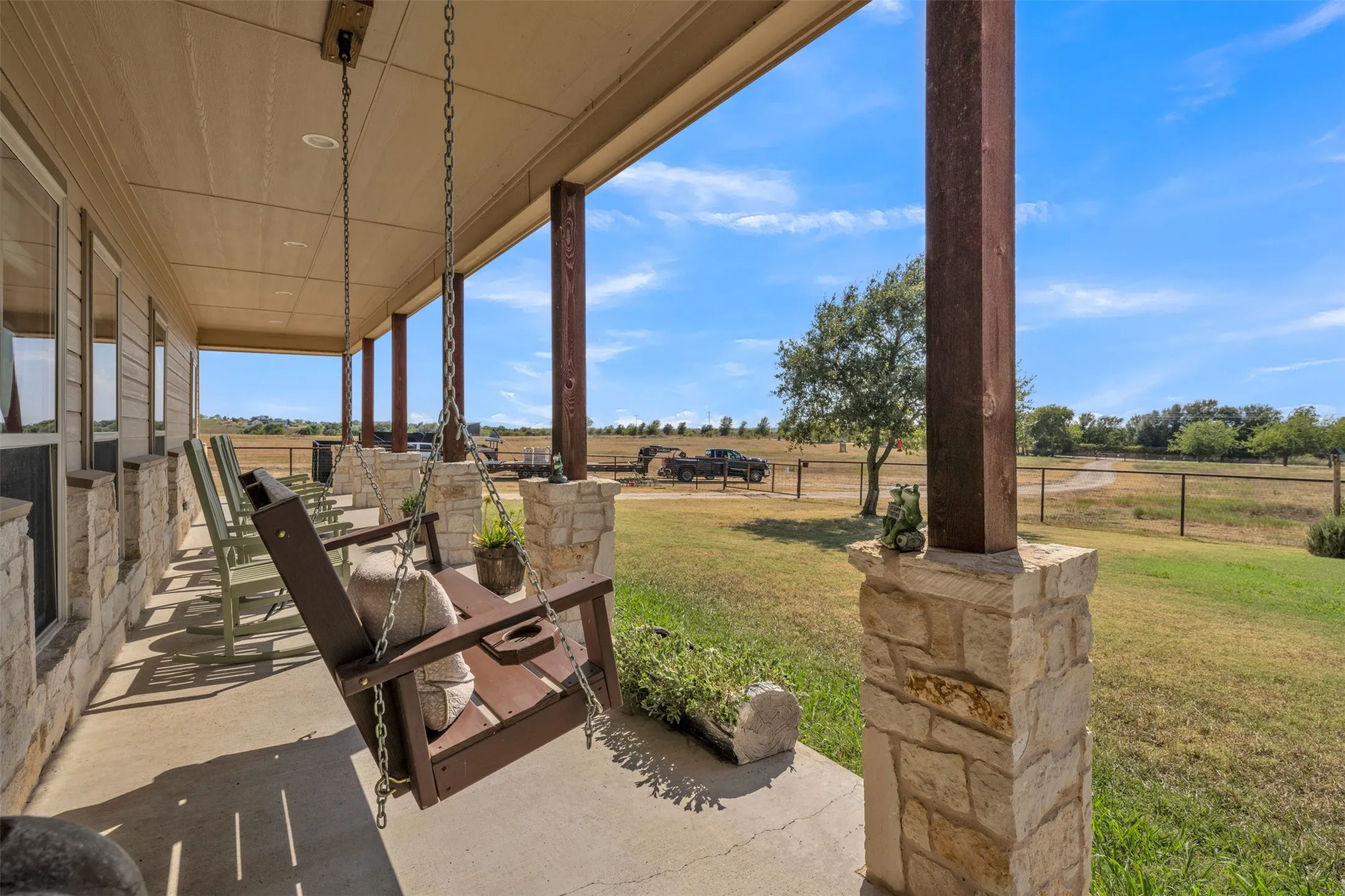 Expansive covered porch featuring stone-clad columns, wood-finish support beams, and recessed lighting