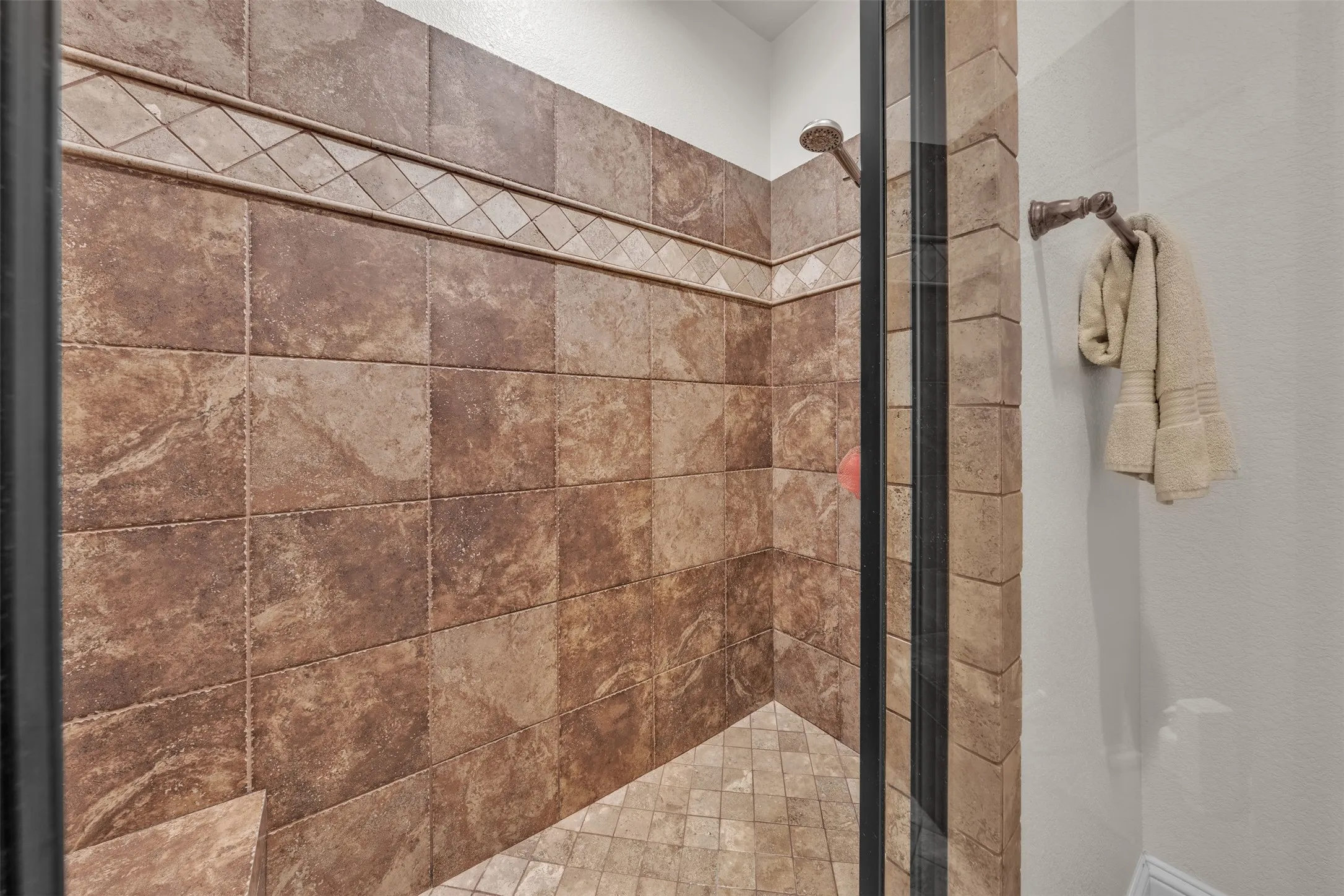 Tiled shower enclosure featuring a decorative accent band and glass door